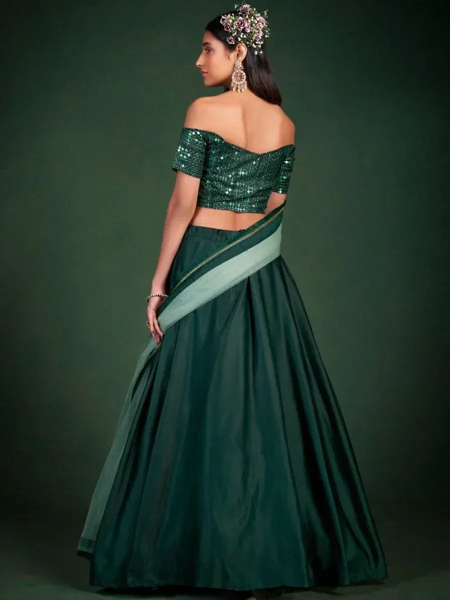 Emerald green sequin off-shoulder lehenga choli with floral hair accessory, perfect for Indian ethnic wear events.