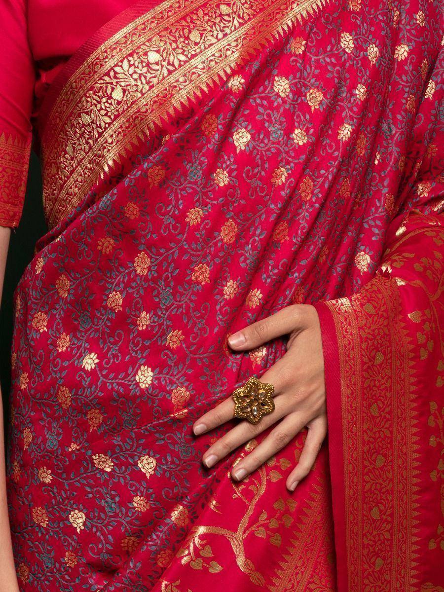 Red ethnic saree with gold floral embroidery and intricate border, styled with matching blouse and statement ring