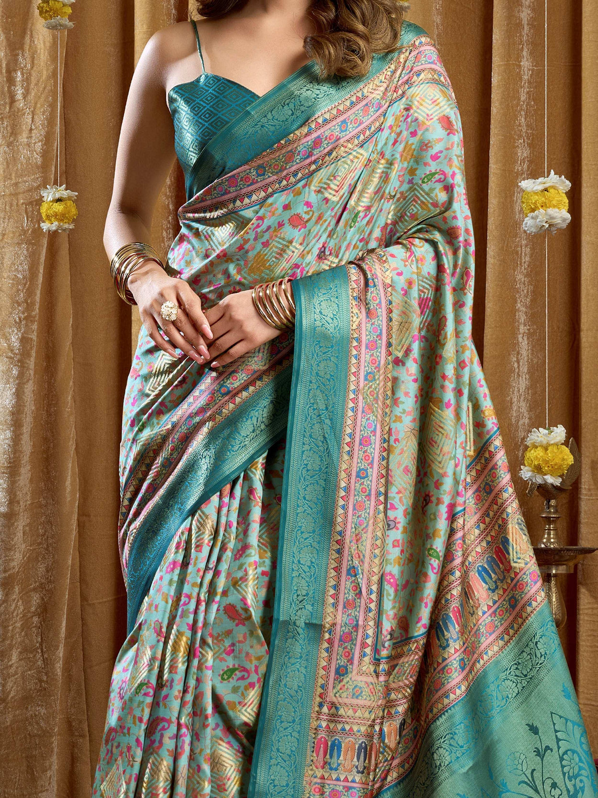 Teal printed saree with floral and geometric patterns, paired with matching blouse and gold bangles