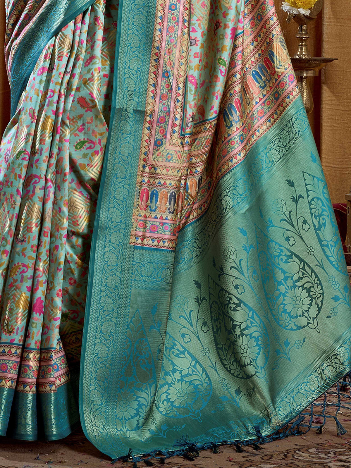 Teal designer saree with floral paisley patterns and vibrant border details