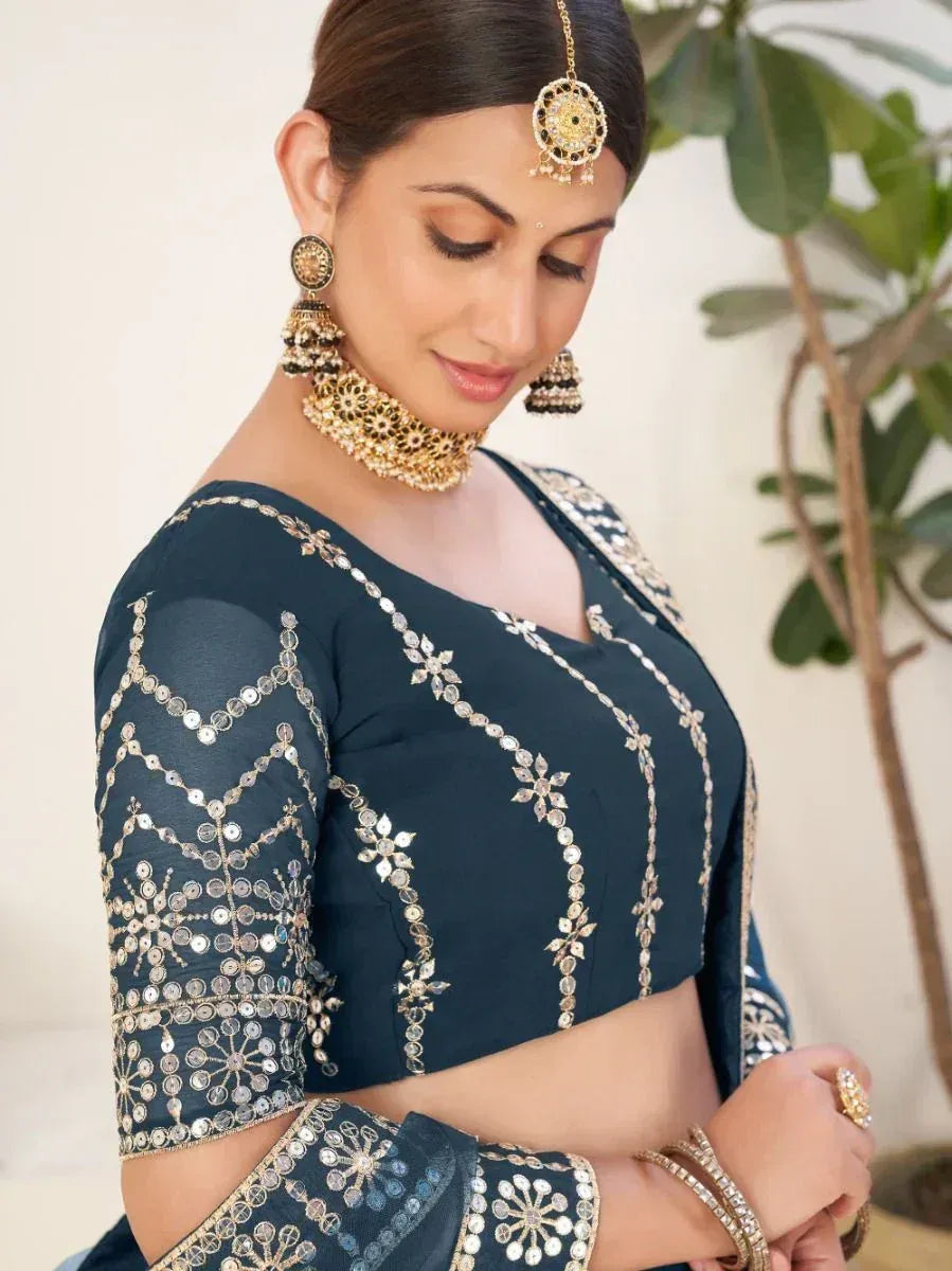 Dark blue embroidered blouse with mirror work, paired with traditional Indian jewelry for ethnic wear.