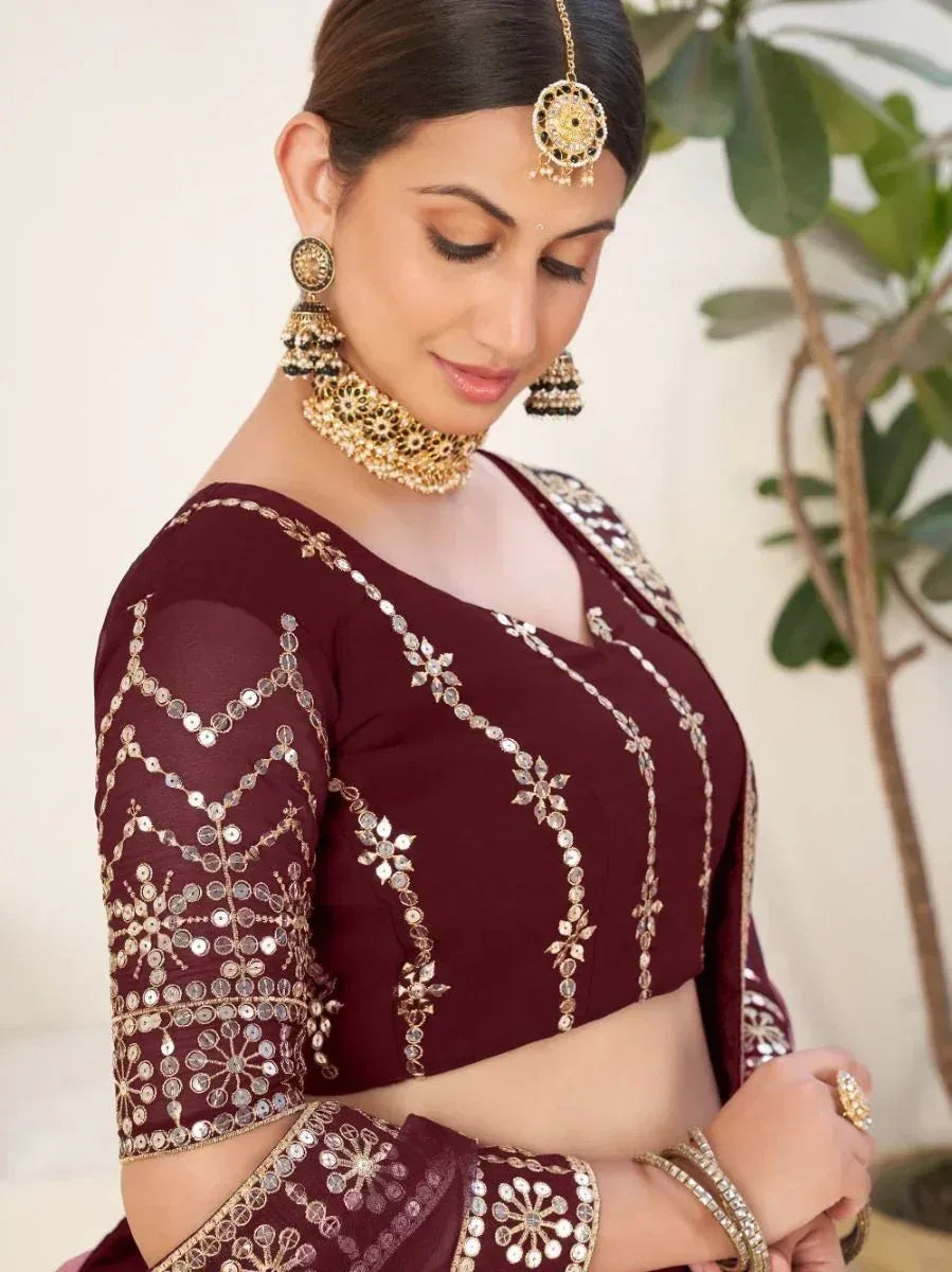 Maroon designer lehenga choli with mirror work and gold embroidery, paired with traditional jewelry