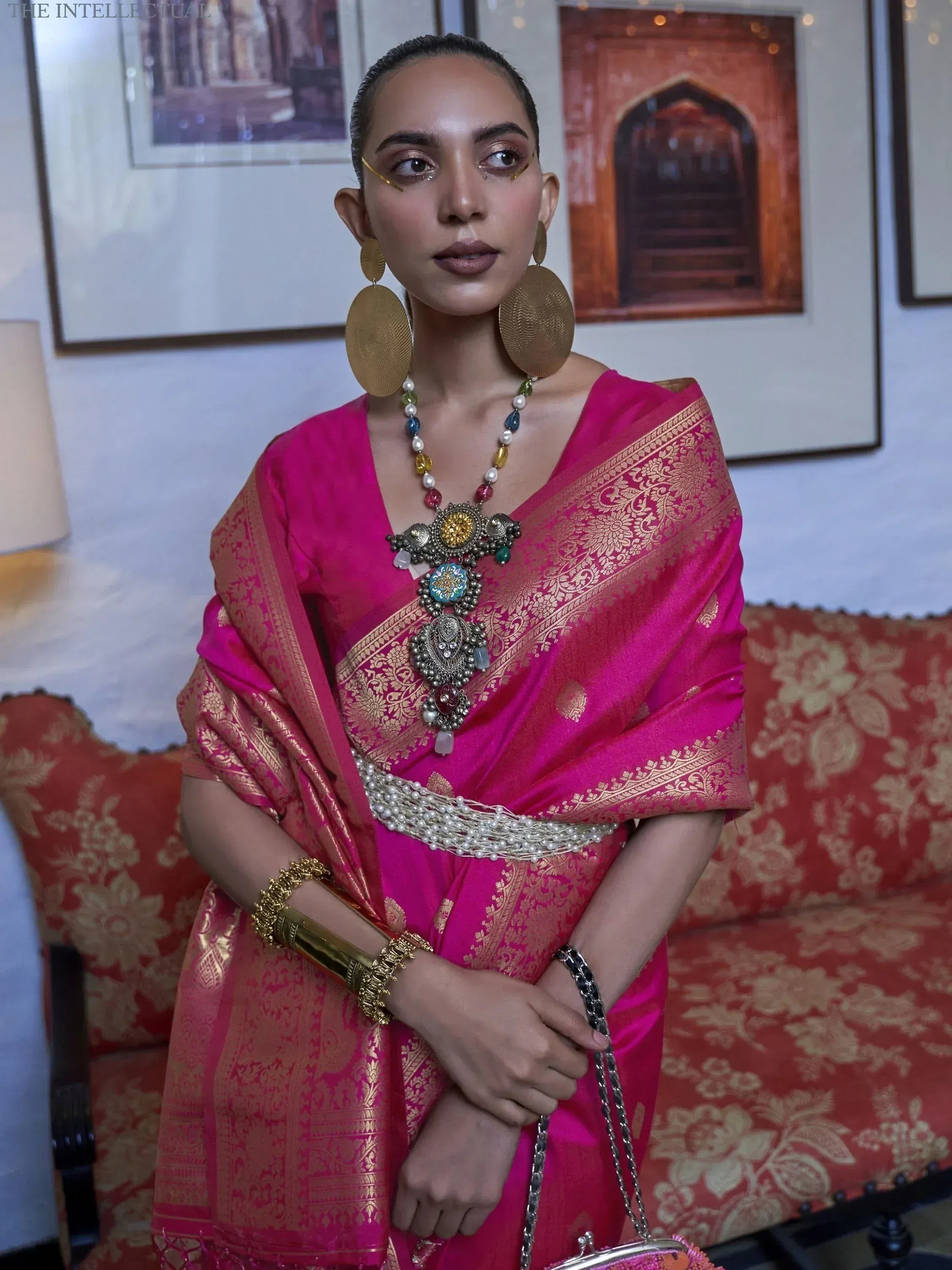 Woman in vibrant pink silk saree with gold zari, statement jewelry, and traditional Indian ethnic wear styling