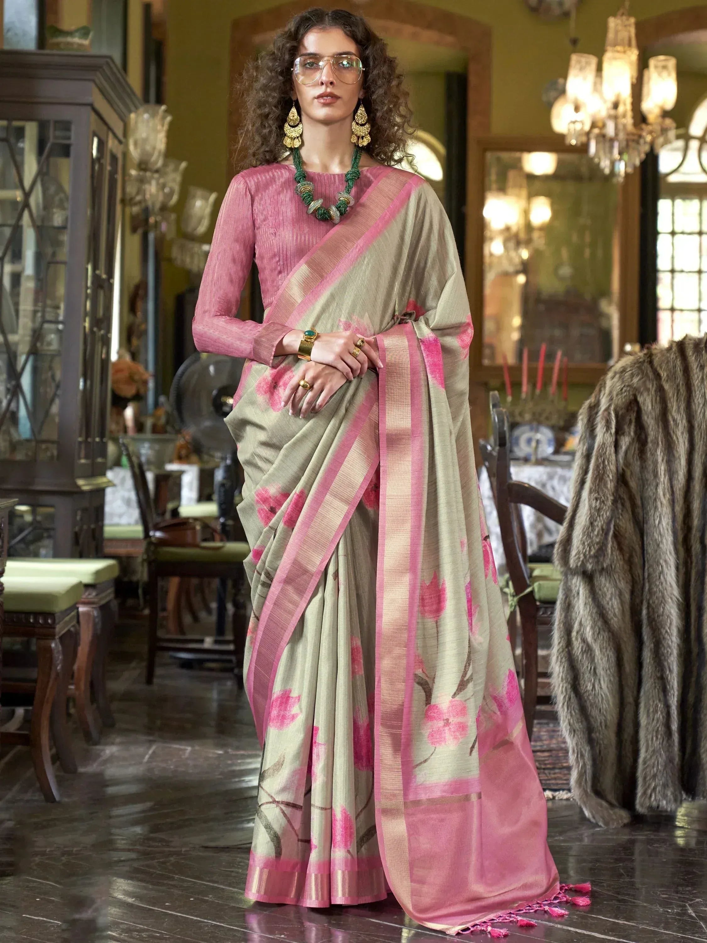 Woman in elegant beige saree with pink floral print and border, paired with pink blouse, perfect for Indian ethnic occasions.