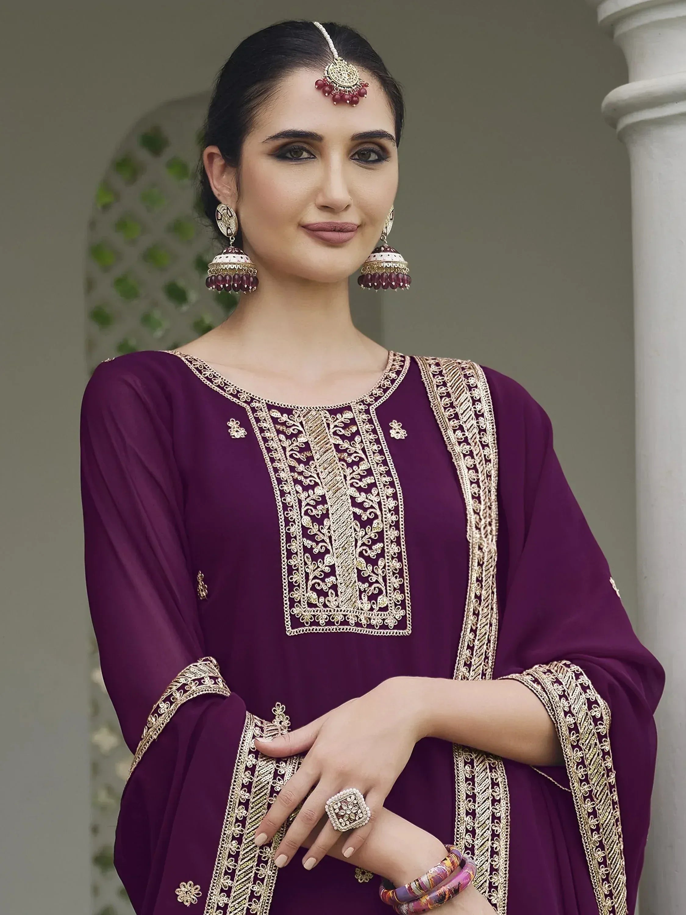 Woman in purple embroidered ethnic salwar kameez with traditional jewelry