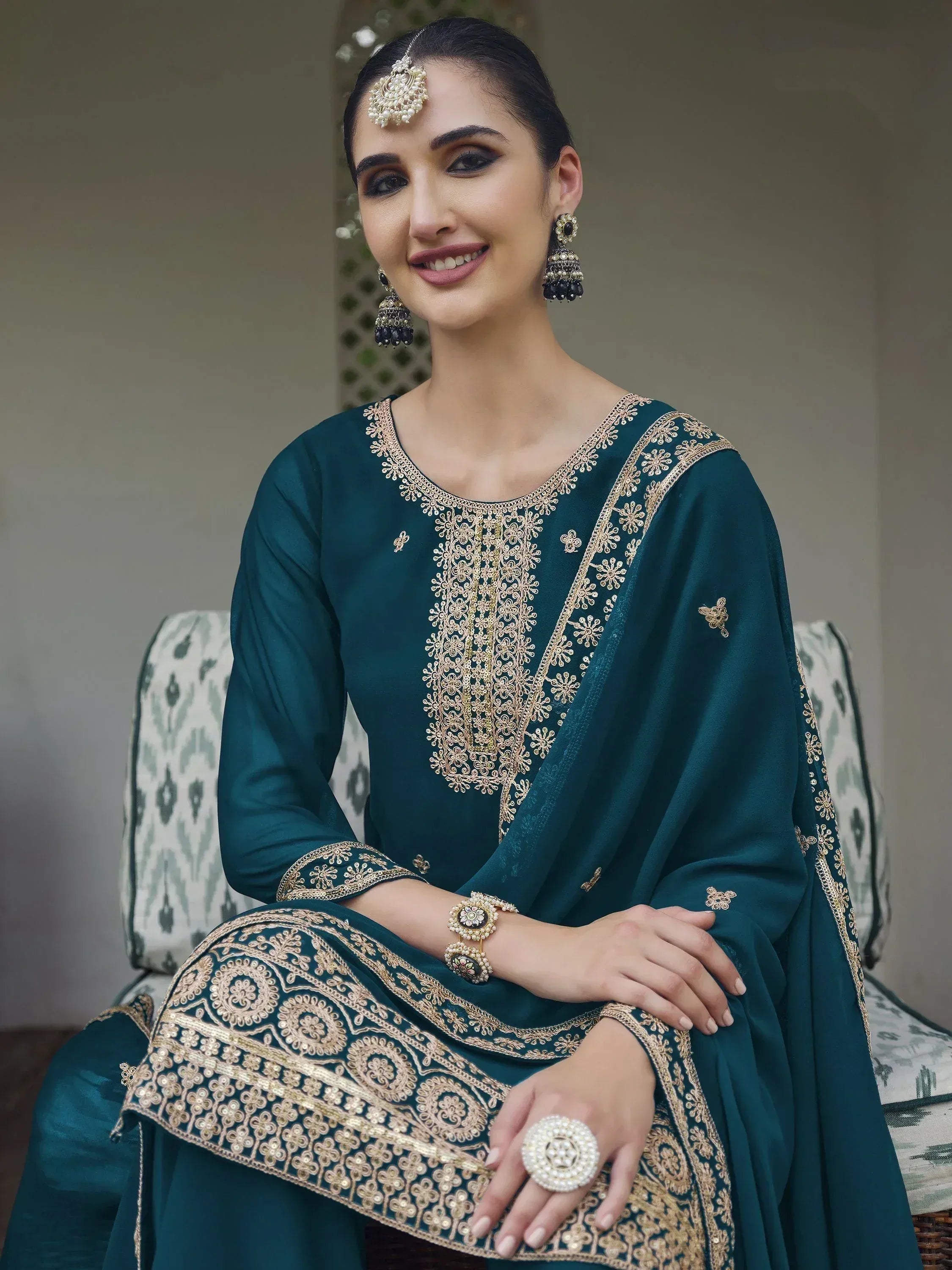 Woman in teal embroidered salwar kameez with matching dupatta and traditional jewelry