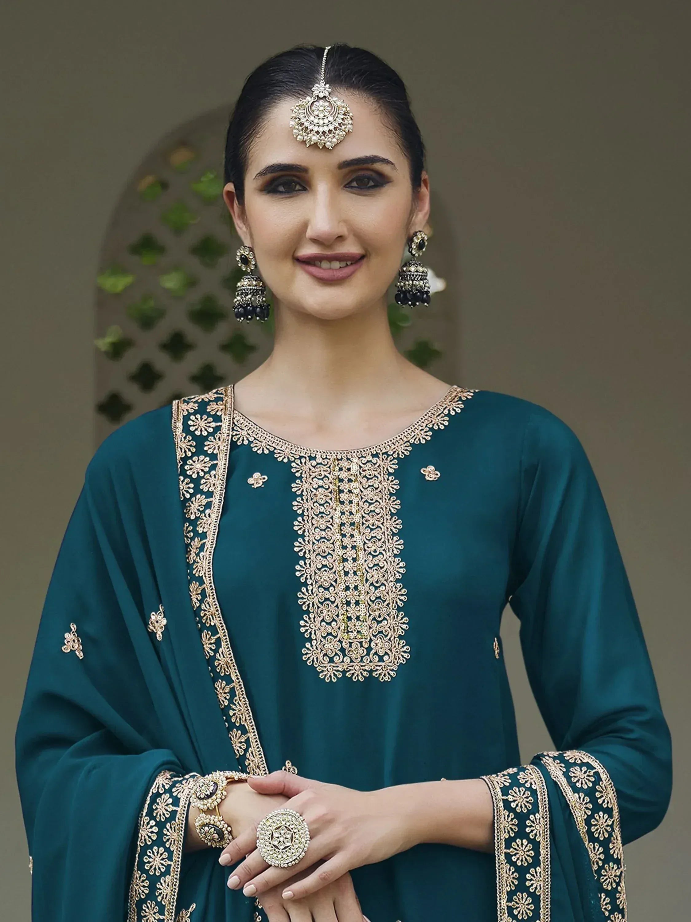 Woman wearing teal embroidered salwar kameez with gold jewelry and matching dupatta
