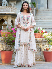 Woman in embroidered Indian ethnic palazzo suit standing outdoors near floral decor