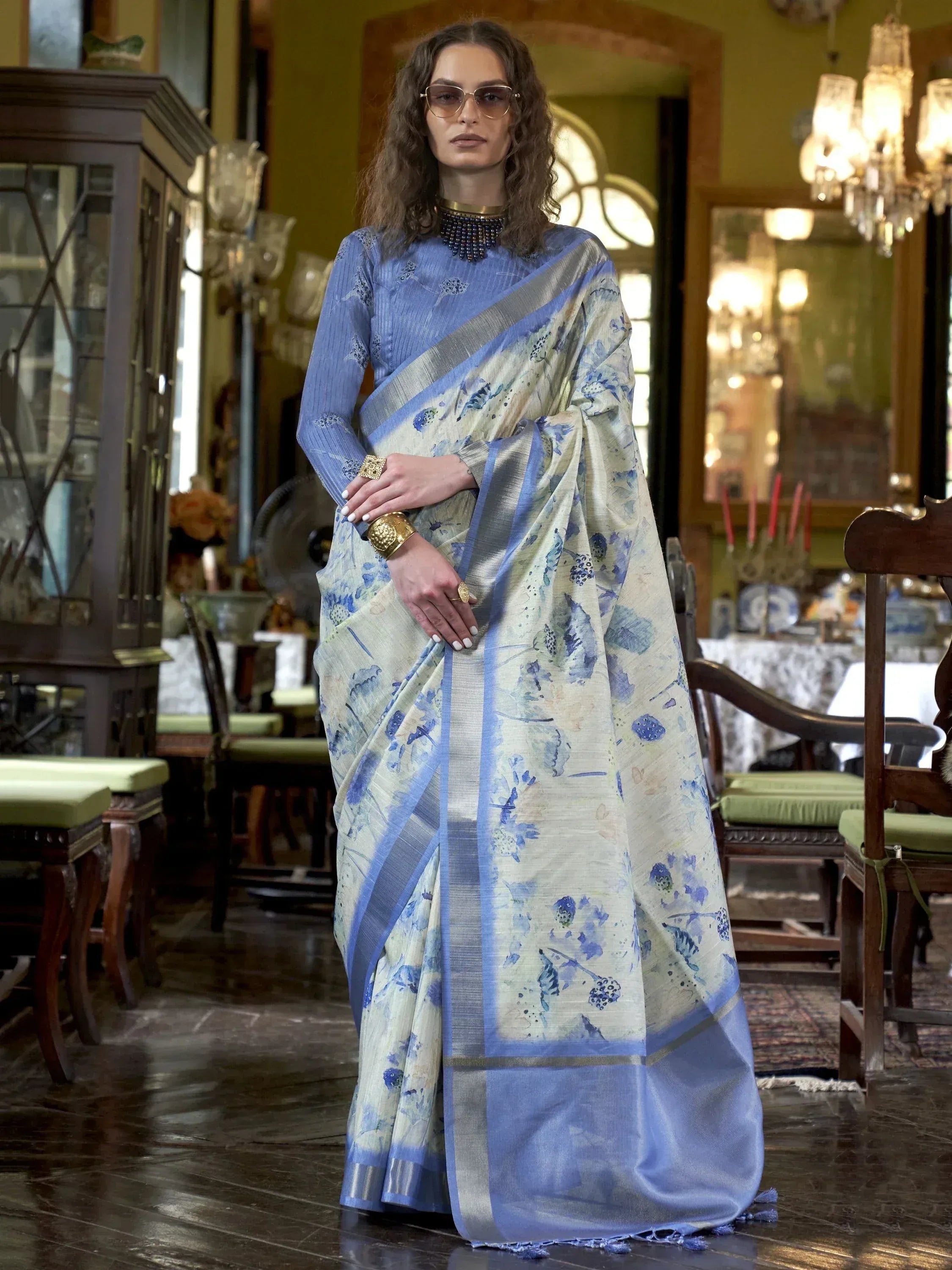 Elegant blue floral print saree with silver border, styled with matching blouse and gold jewelry for ethnic wear.