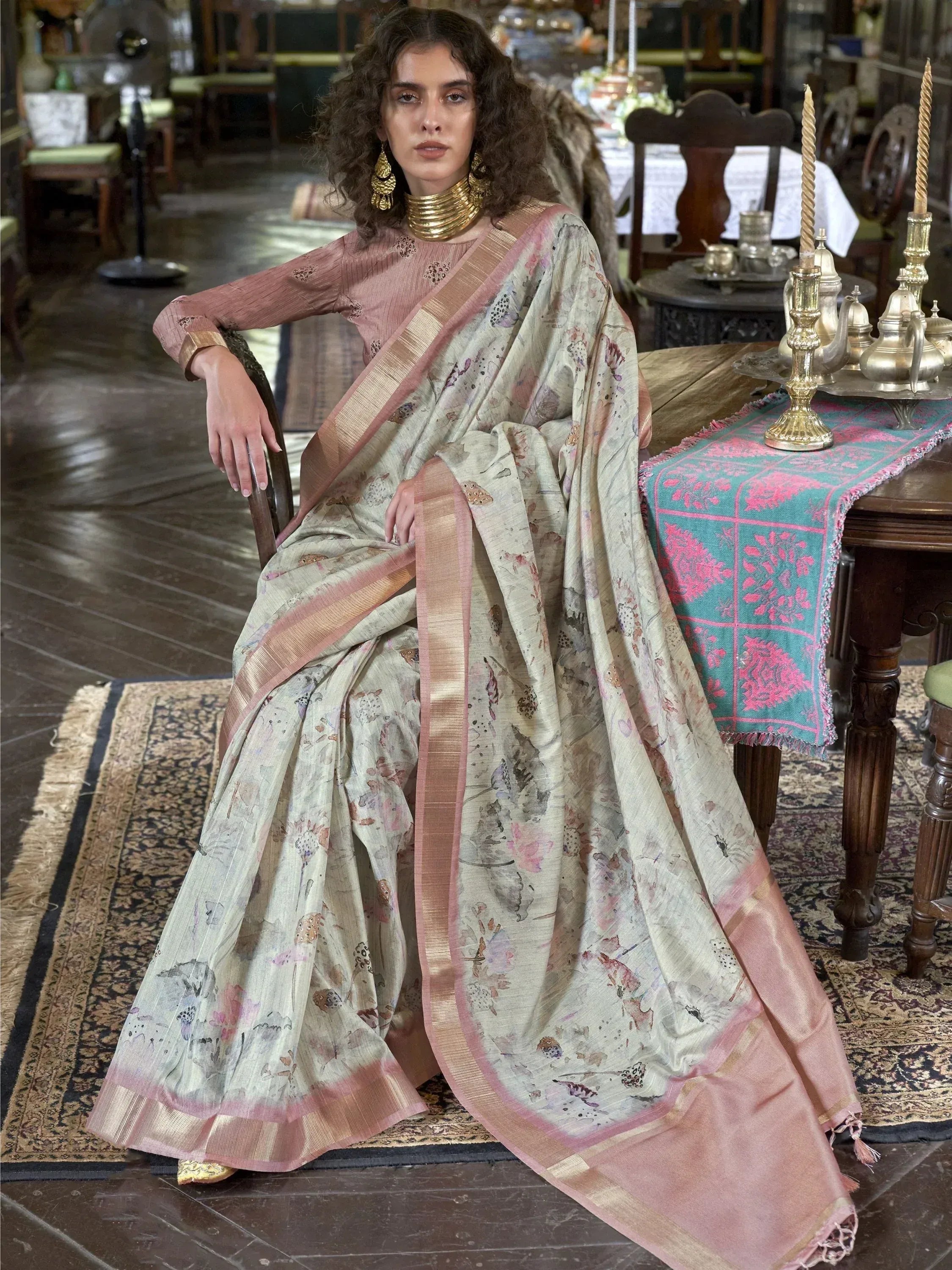 Woman in floral print saree with pink border, ethnic Indian wear, styled with gold jewelry