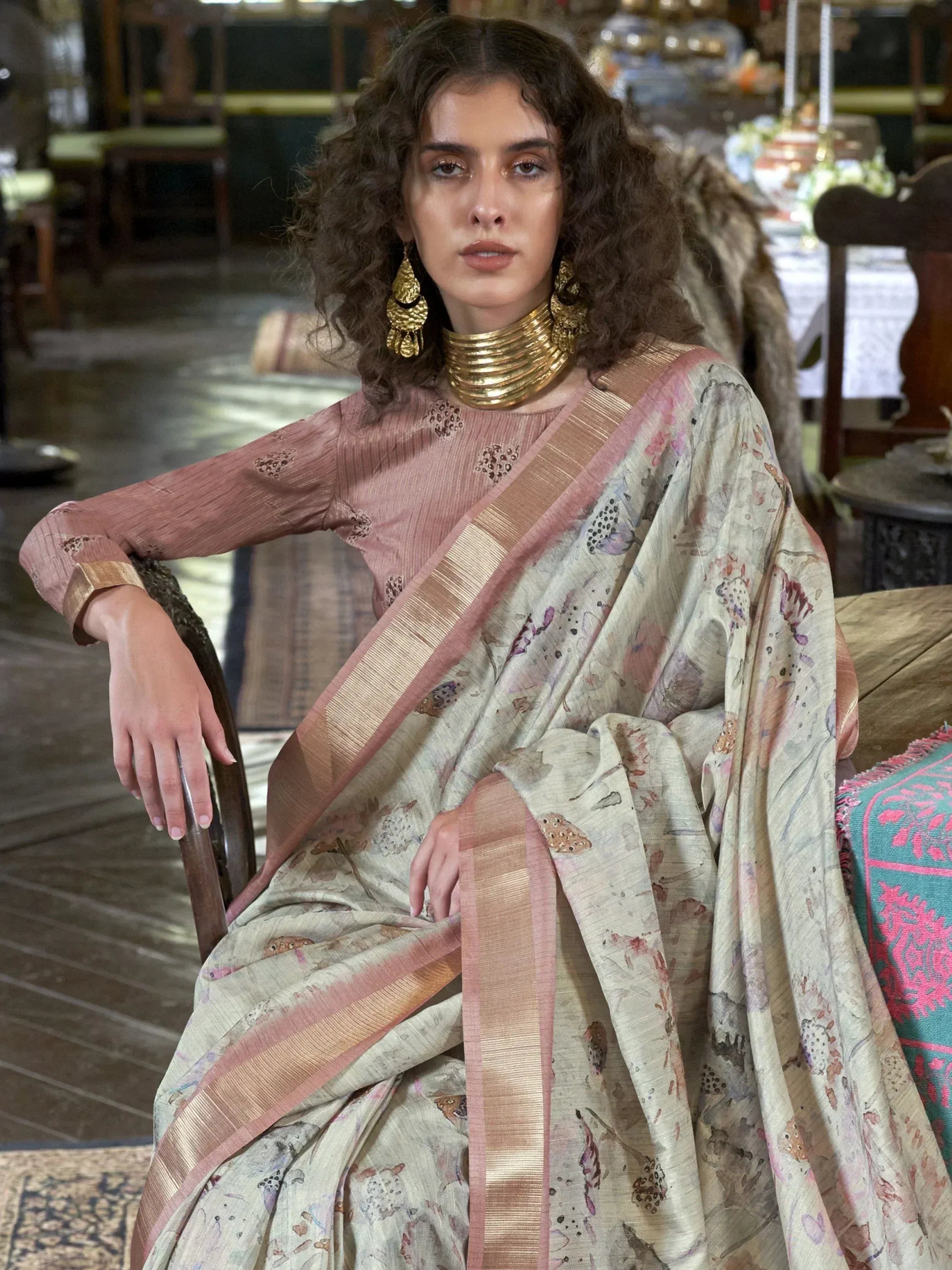 Woman in floral printed saree with gold border, styled with ethnic jewelry for traditional Indian wear