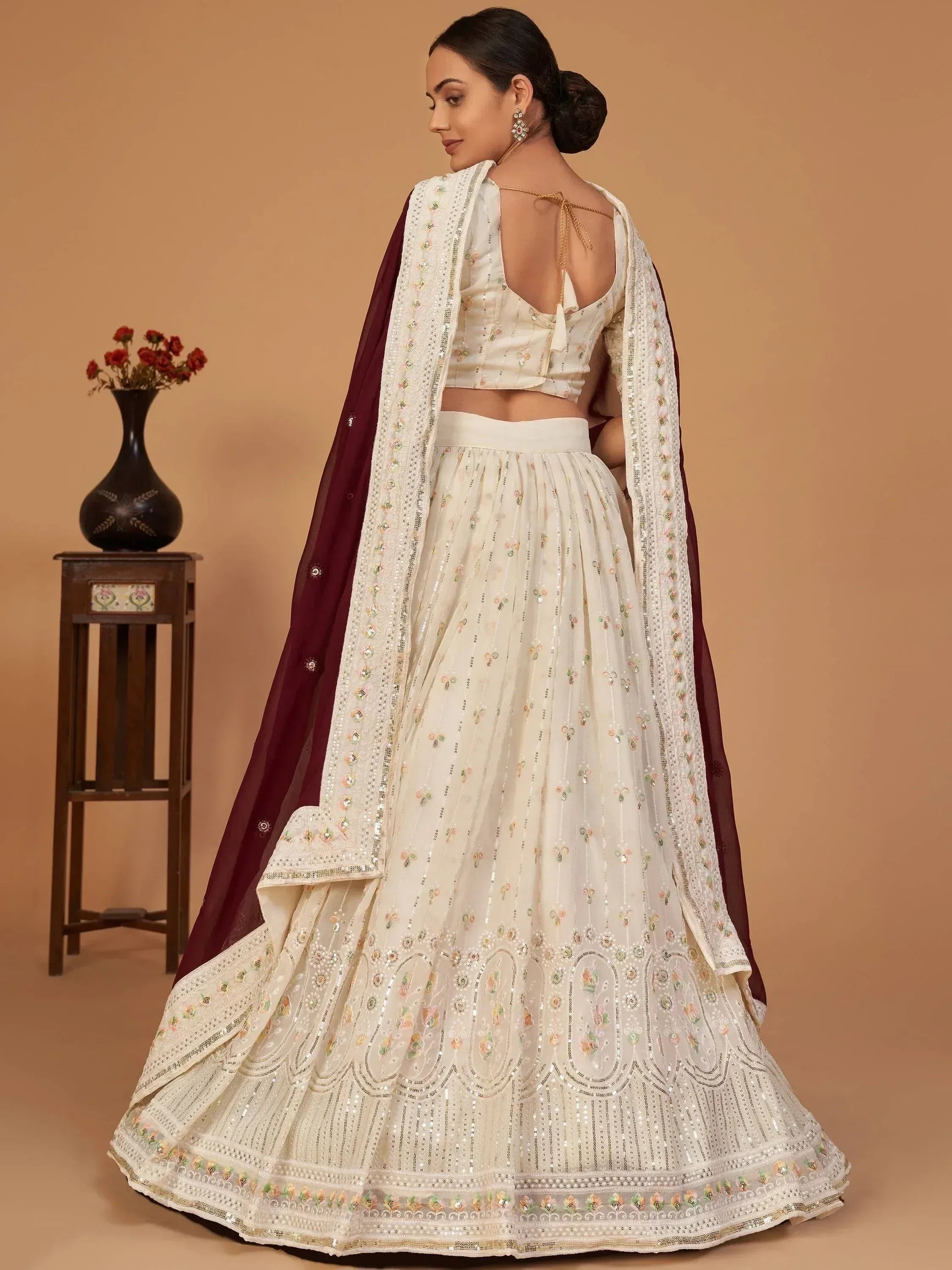 Elegant ivory lehenga choli with floral embroidery and maroon dupatta, perfect for Indian weddings or festive occasions.