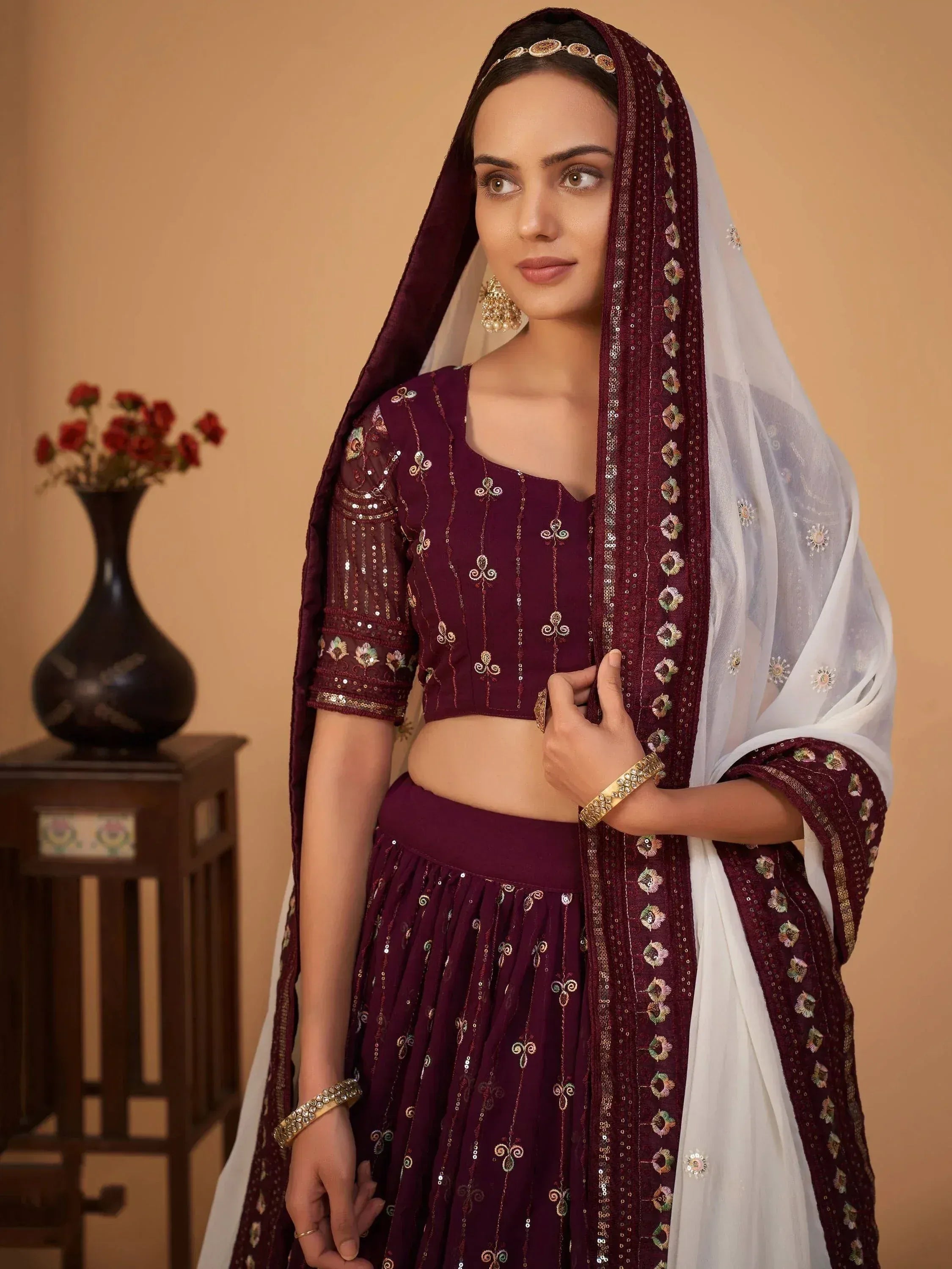 Elegant maroon lehenga choli with gold embroidery and white dupatta, perfect for Indian ethnic wear occasions.