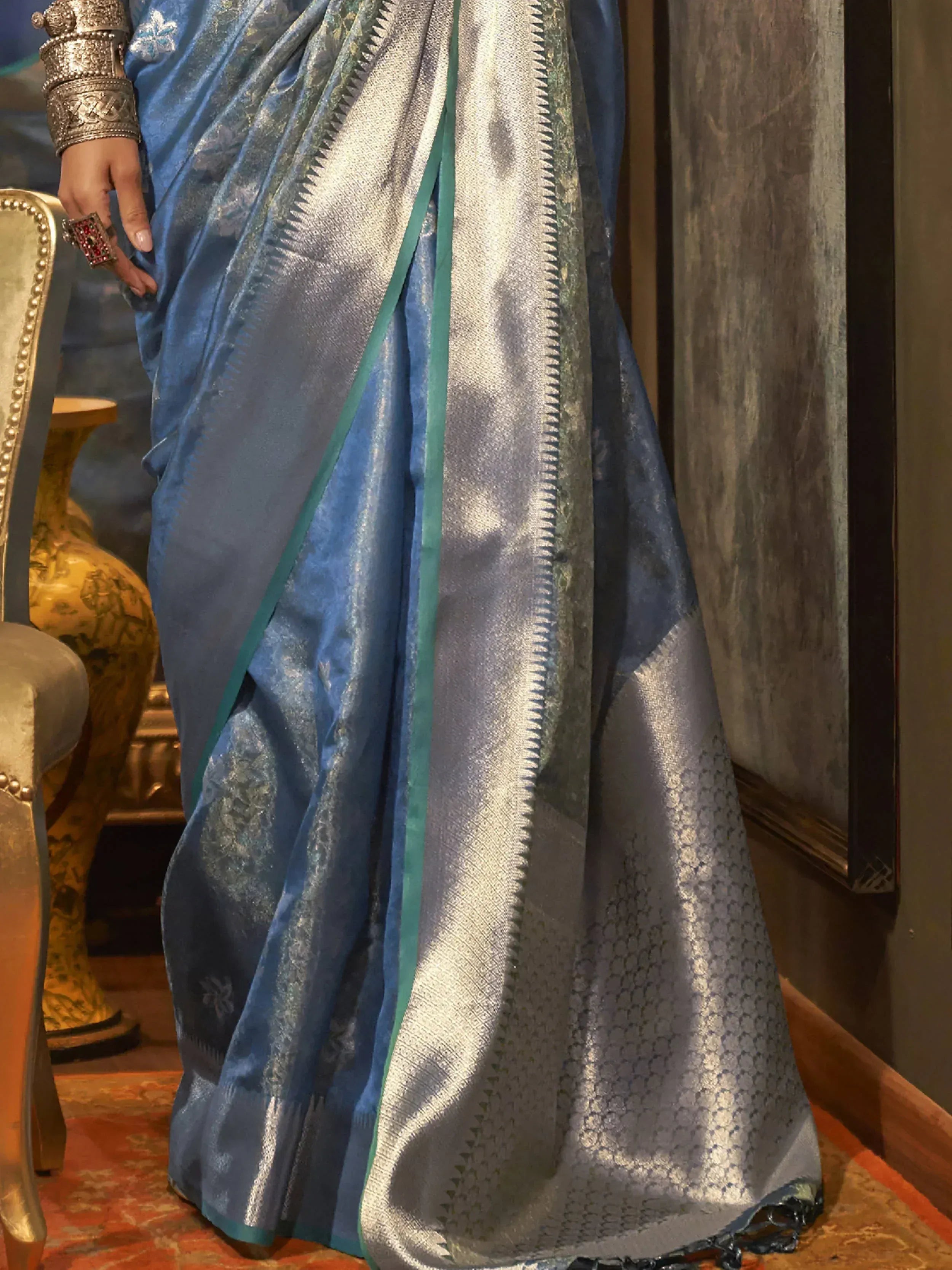 Blue and silver designer saree with intricate woven patterns and contrasting border, styled with traditional jewelry.