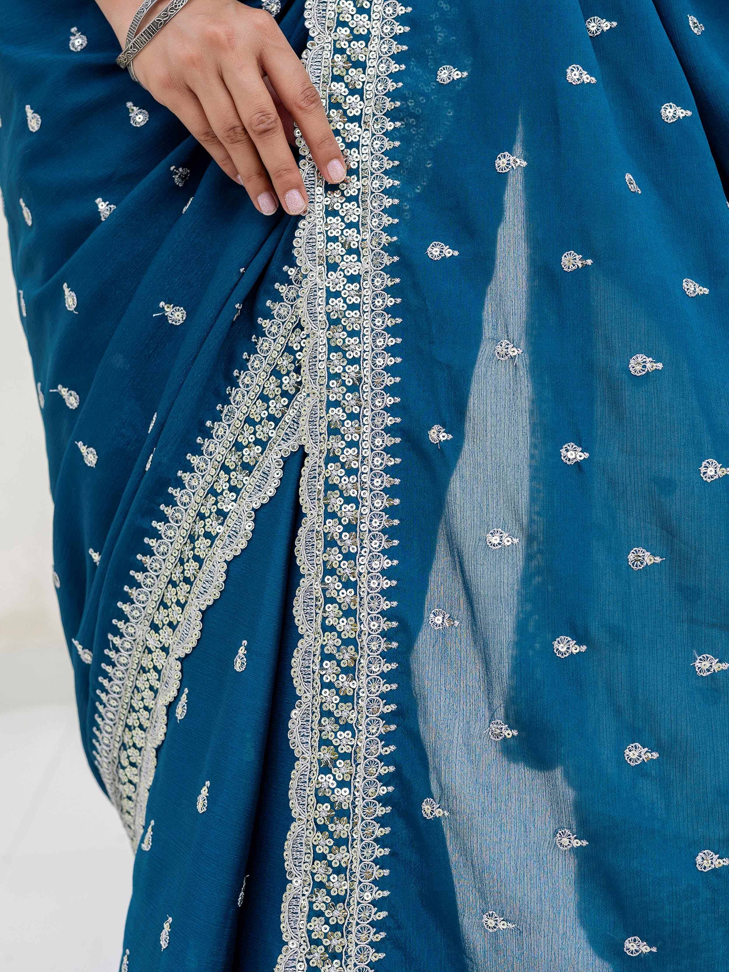 Teal saree with intricate silver embroidery and sequin detailing, perfect for ethnic occasions.