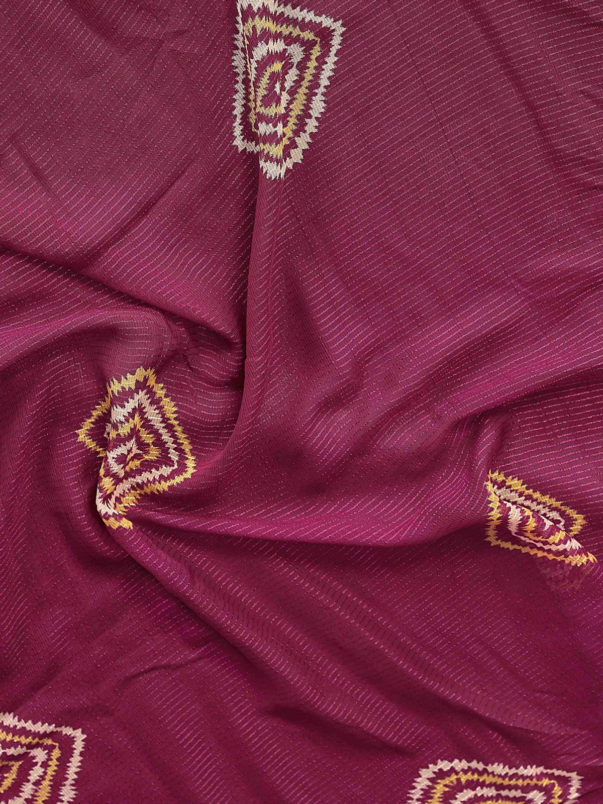 Rich maroon ethnic fabric with gold and cream woven motifs, ideal for designer sarees or lehenga choli.