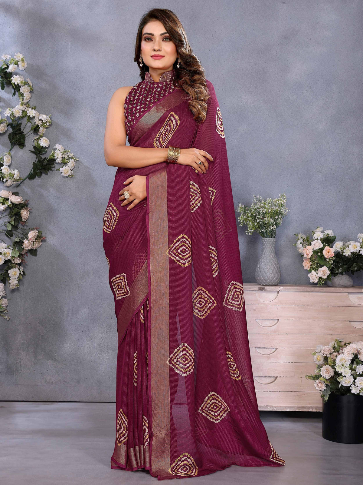 Maroon ethnic saree with geometric embroidery and gold border, styled with matching blouse for festive occasions