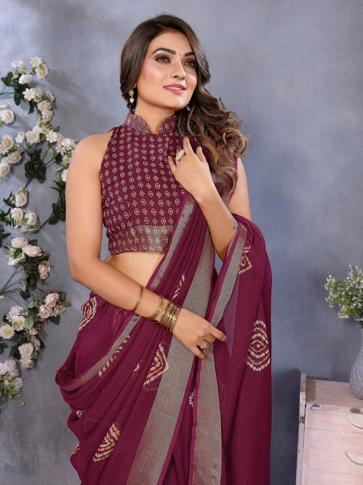 Maroon ethnic saree with gold geometric print and matching blouse, styled with jewelry for festive occasions