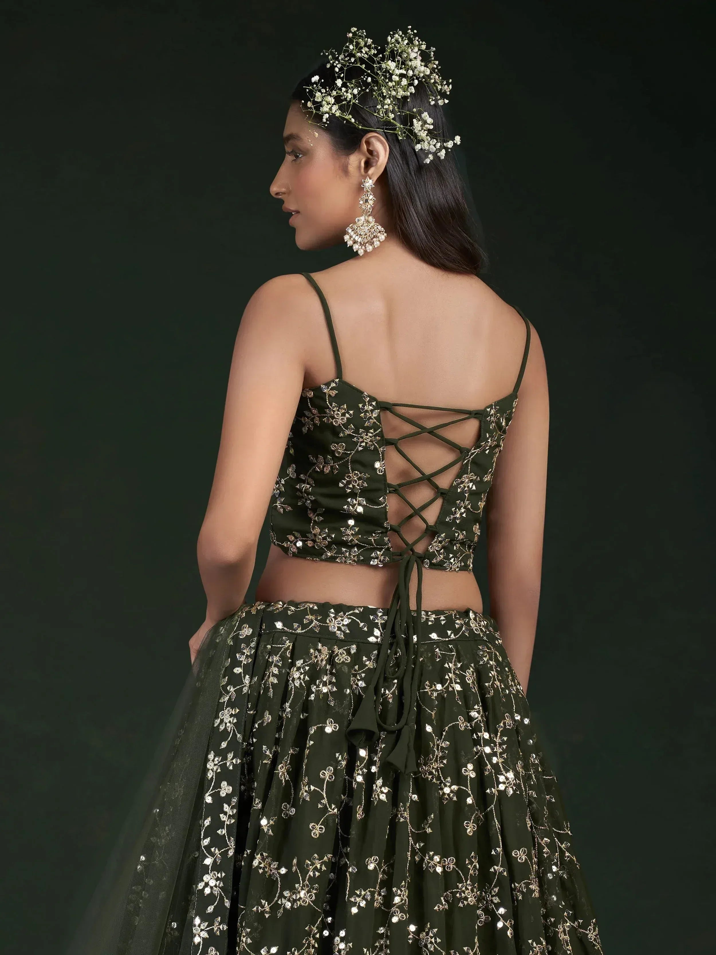 Olive green embroidered lehenga choli with lace-up back, floral hair accessory, and statement earrings