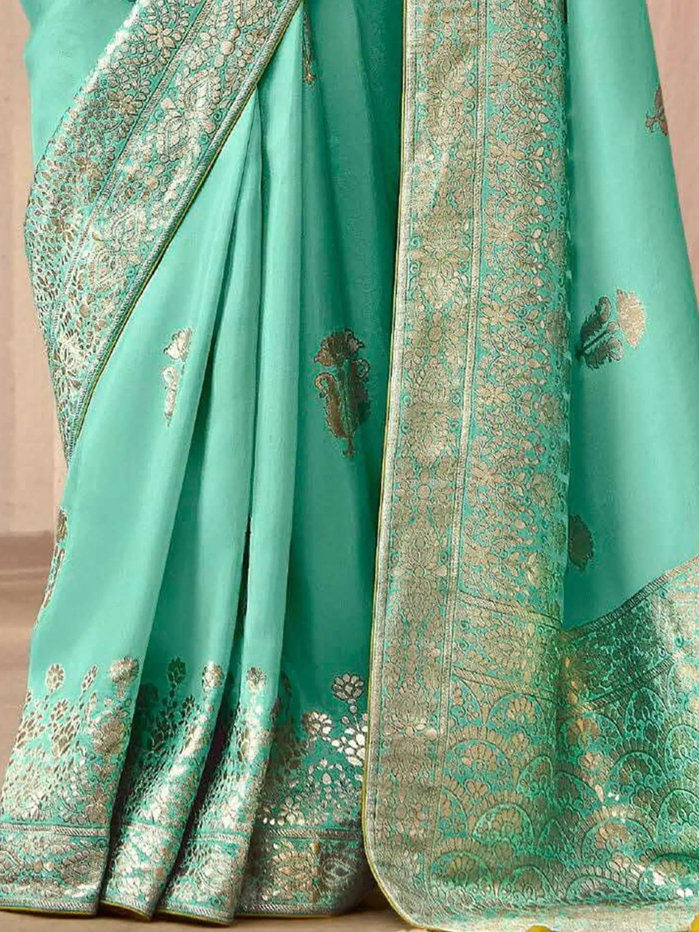 Mint green designer saree with intricate gold zari embroidery and floral motifs, perfect for ethnic occasions.