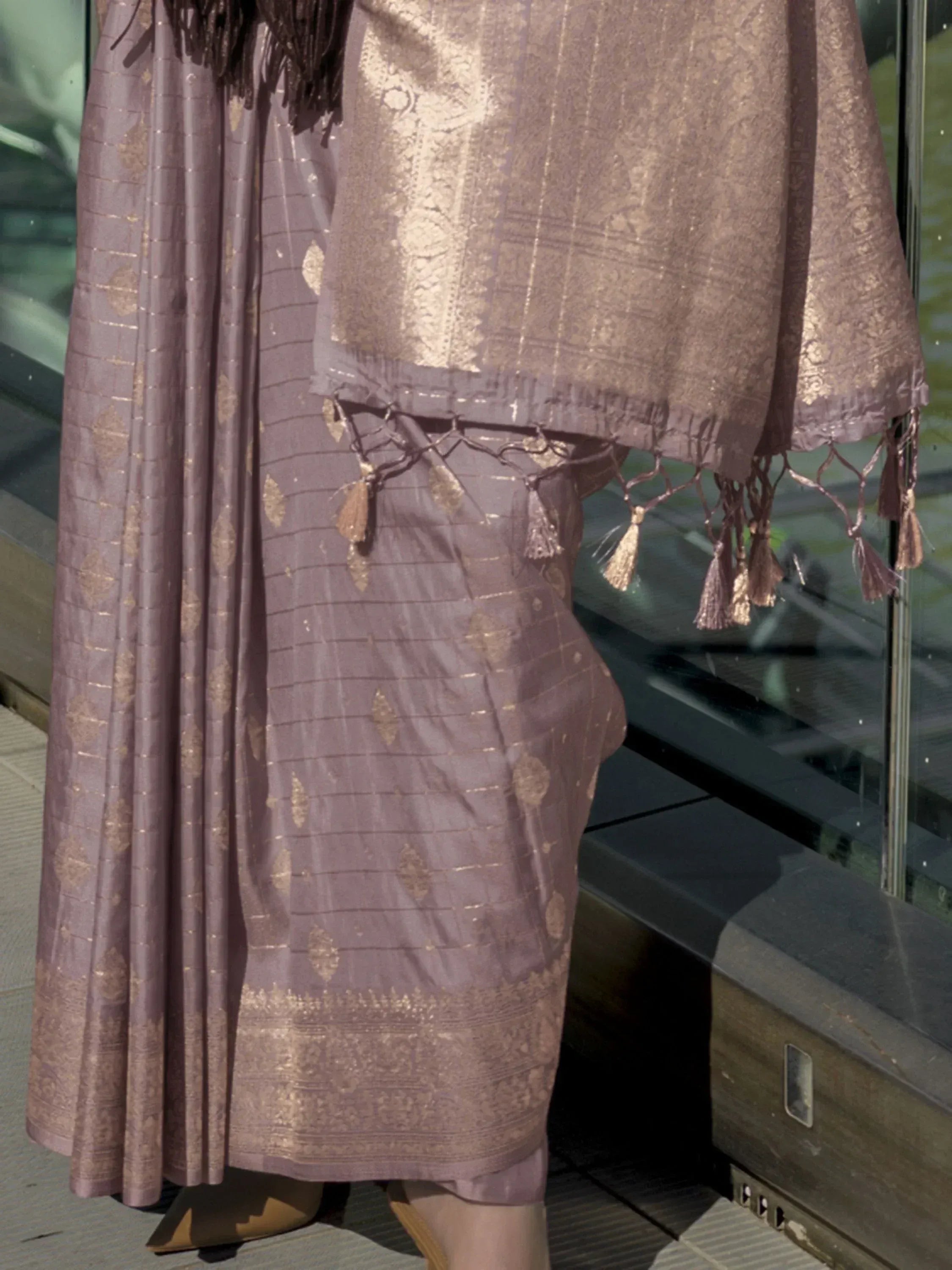 Elegant mauve ethnic gown with gold zari work and tassel detailing, perfect for festive occasions.