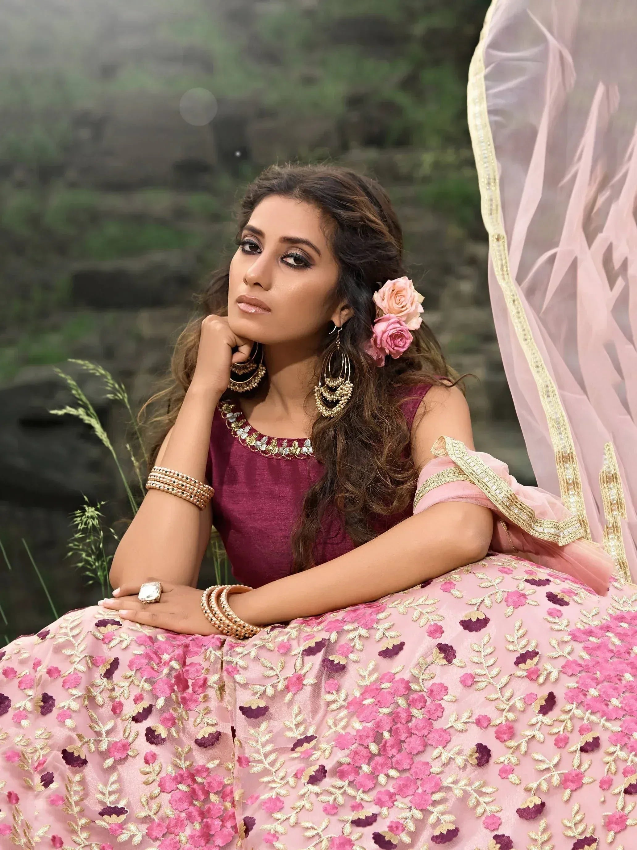 Woman in pink floral embroidered lehenga choli with gold jewelry, perfect for Indian ethnic wear occasions.