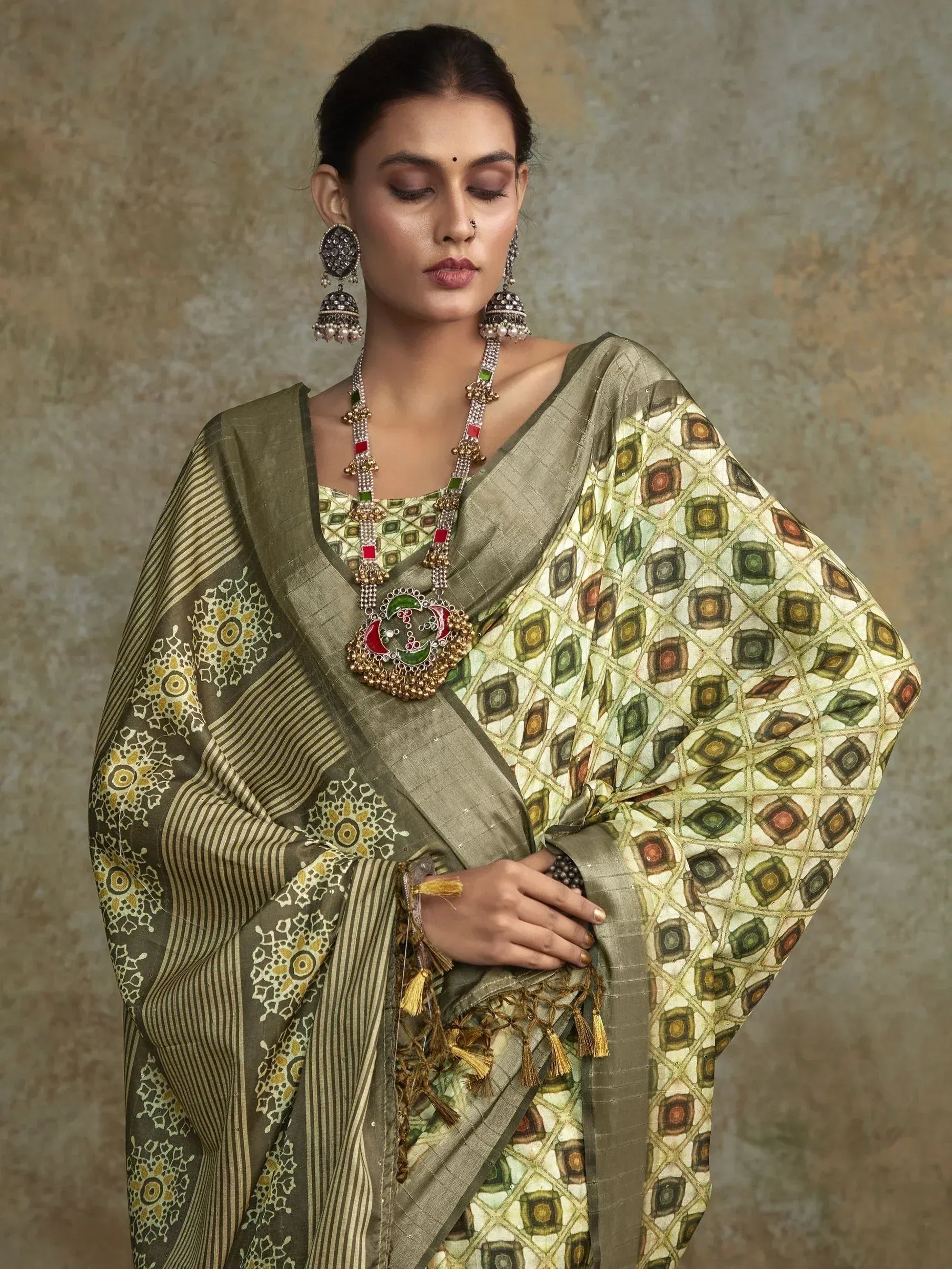 Elegant olive green printed saree with geometric and floral motifs, paired with traditional jewelry for ethnic wear.