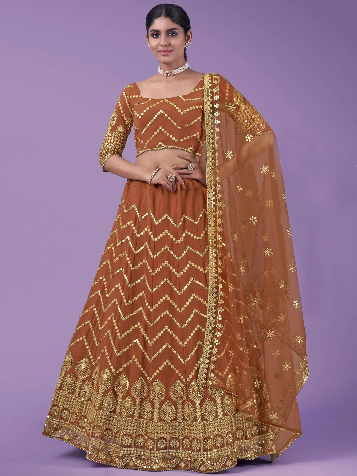 Elegant brown lehenga choli with golden zigzag embroidery and sheer dupatta for Indian ethnic wear