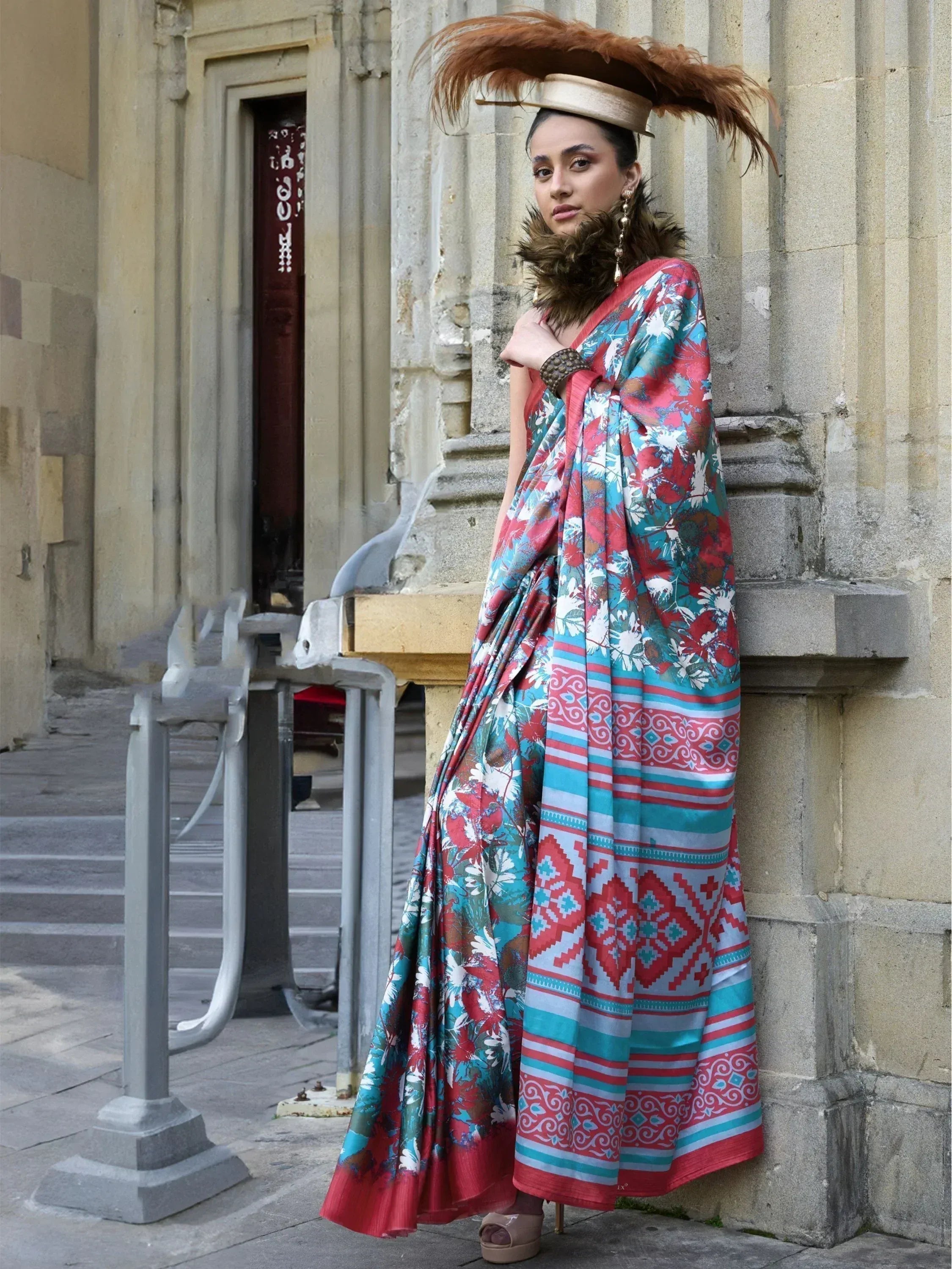 Woman in vibrant floral and geometric print saree with feathered hat, styled for ethnic fashion