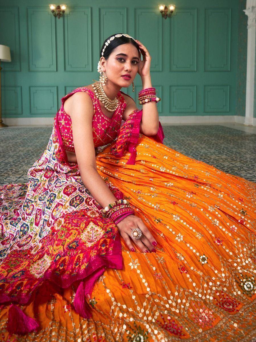 Vibrant orange and pink embroidered lehenga choli with floral patterns, perfect for Indian weddings and festive occasions.