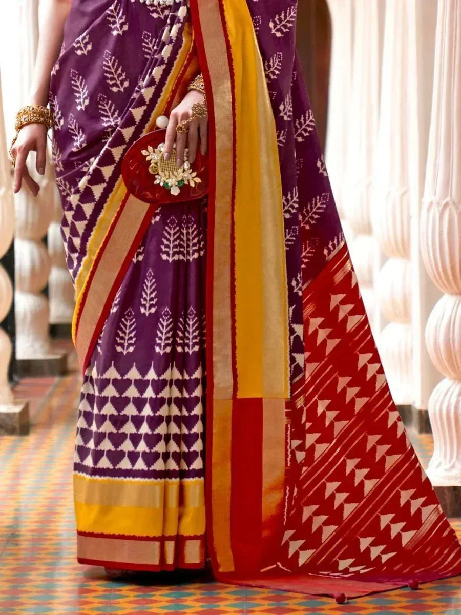 Purple and red ethnic saree with white geometric print, gold border, and matching clutch for Indian occasions