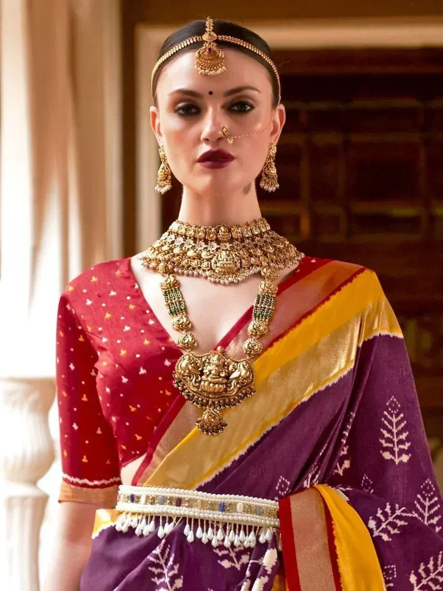 Woman in purple and red ethnic saree with gold jewelry, traditional Indian bridal wear