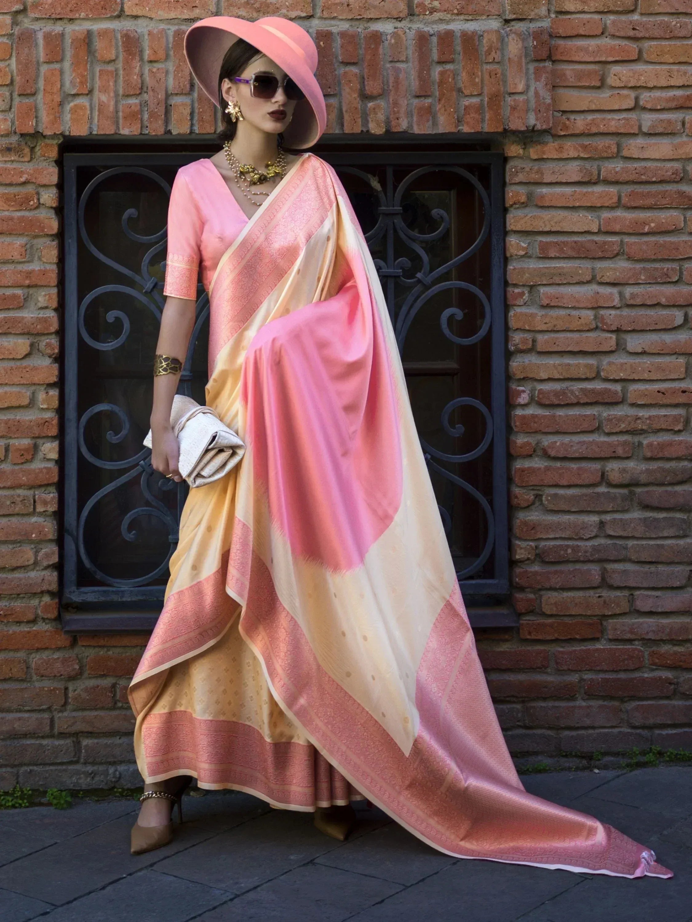 Pink and gold designer saree with matching blouse, styled with wide-brim hat and gold jewelry for ethnic wear