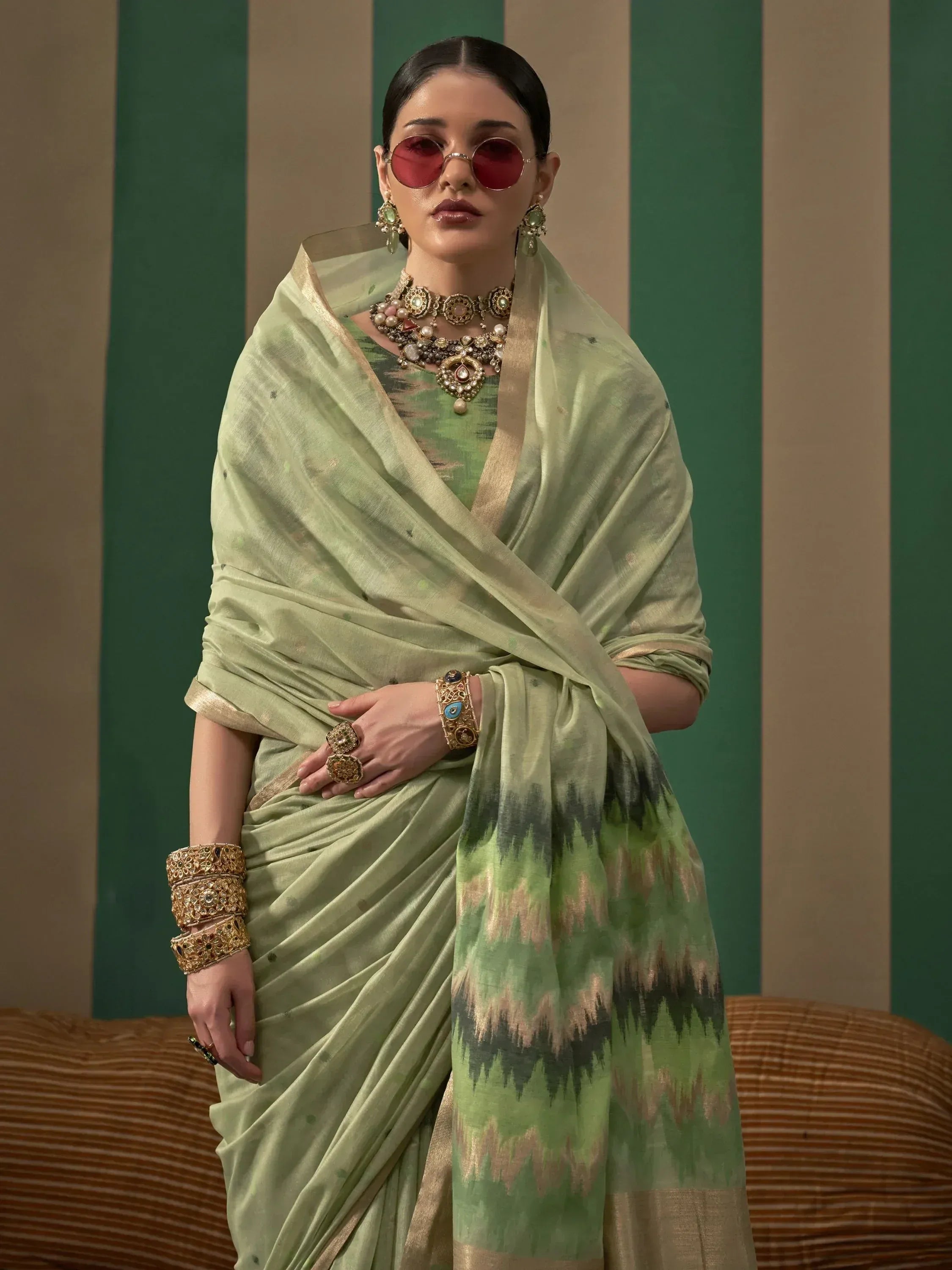 Stylish green saree with ikat print, gold border, and traditional jewelry for ethnic wear