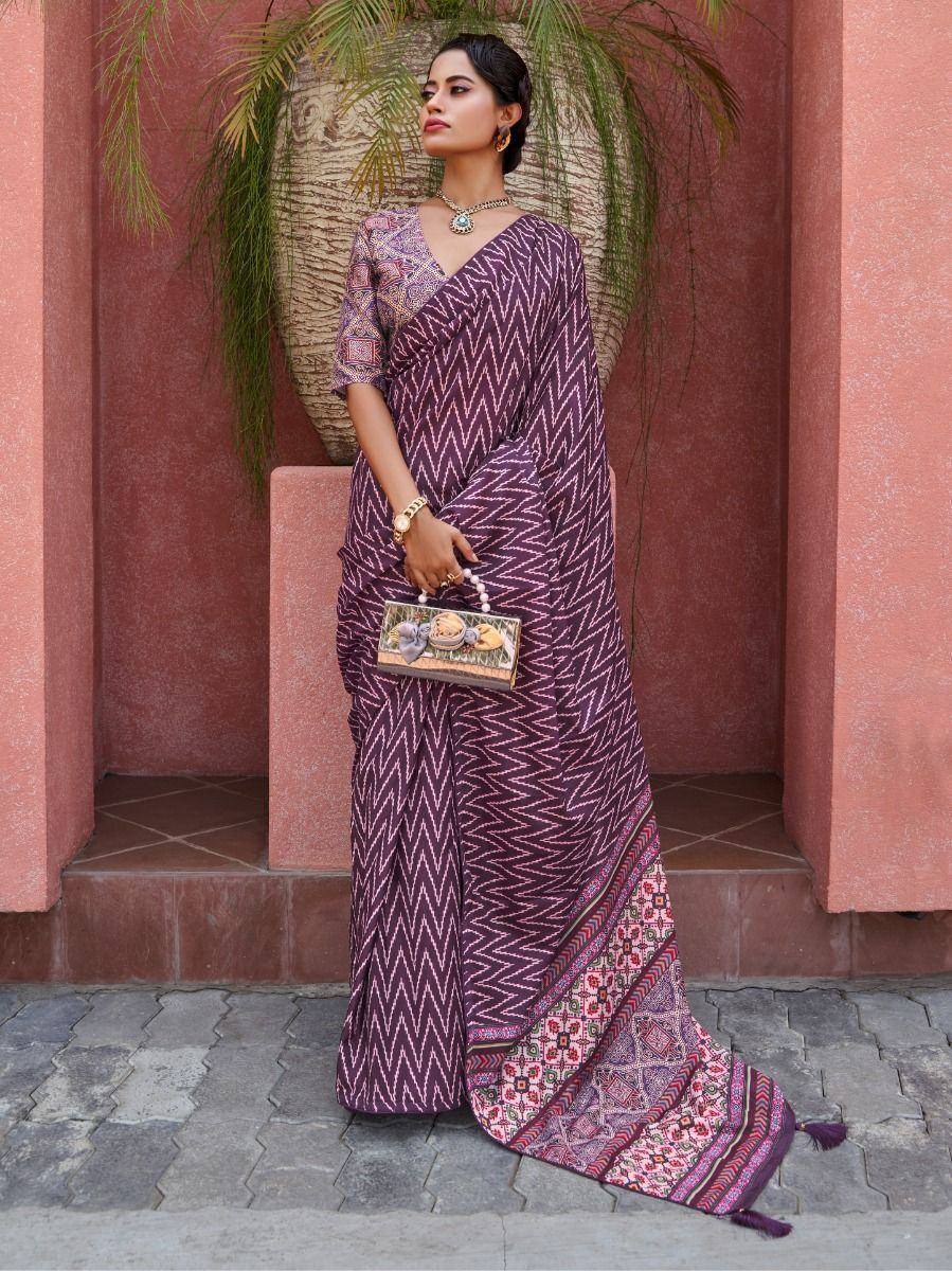 Woman in purple printed saree with ethnic blouse, holding clutch, styled for Indian occasions
