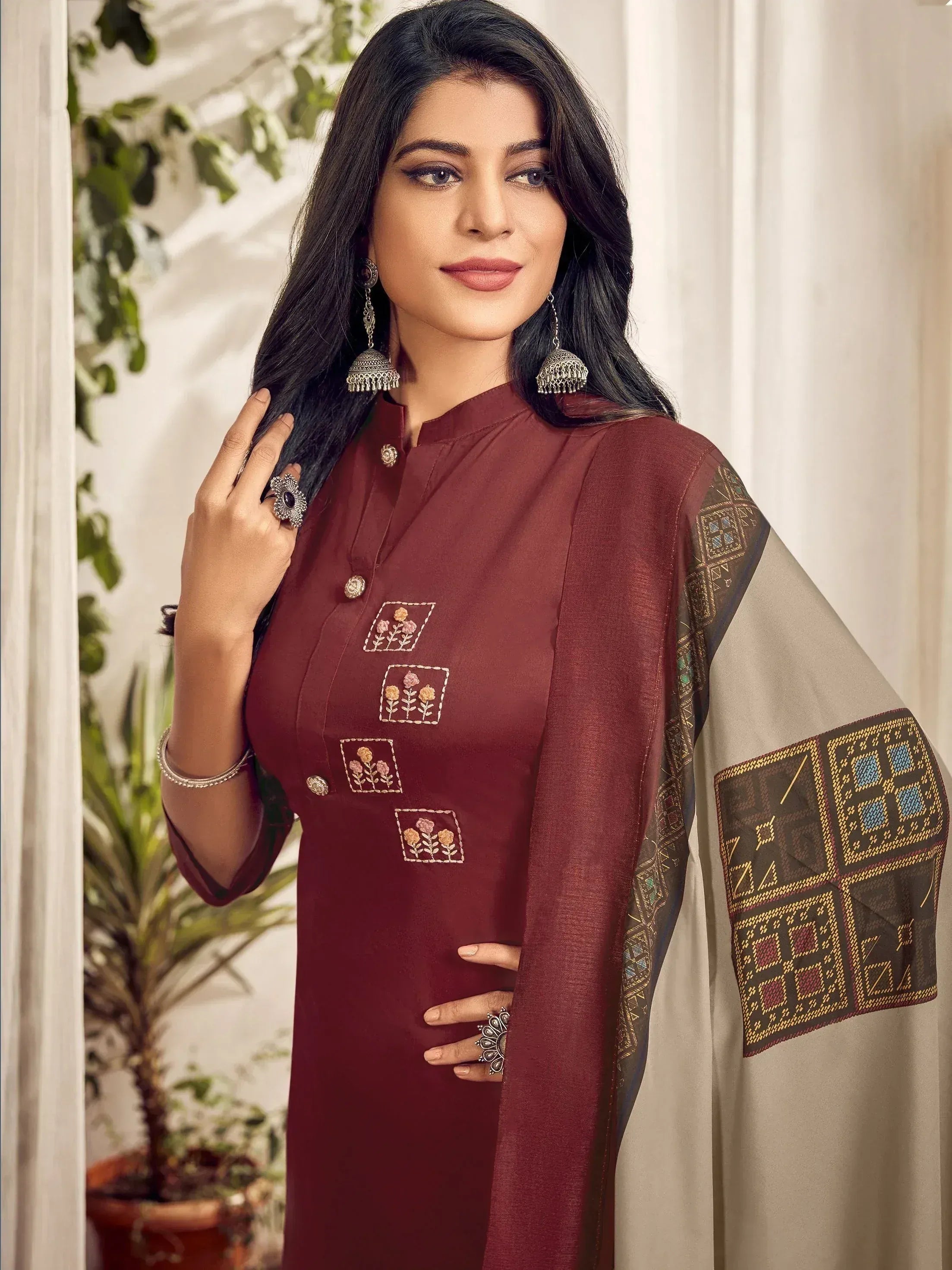 Maroon embroidered kurta with floral motifs and geometric sleeve design, styled with jhumka earrings for ethnic wear