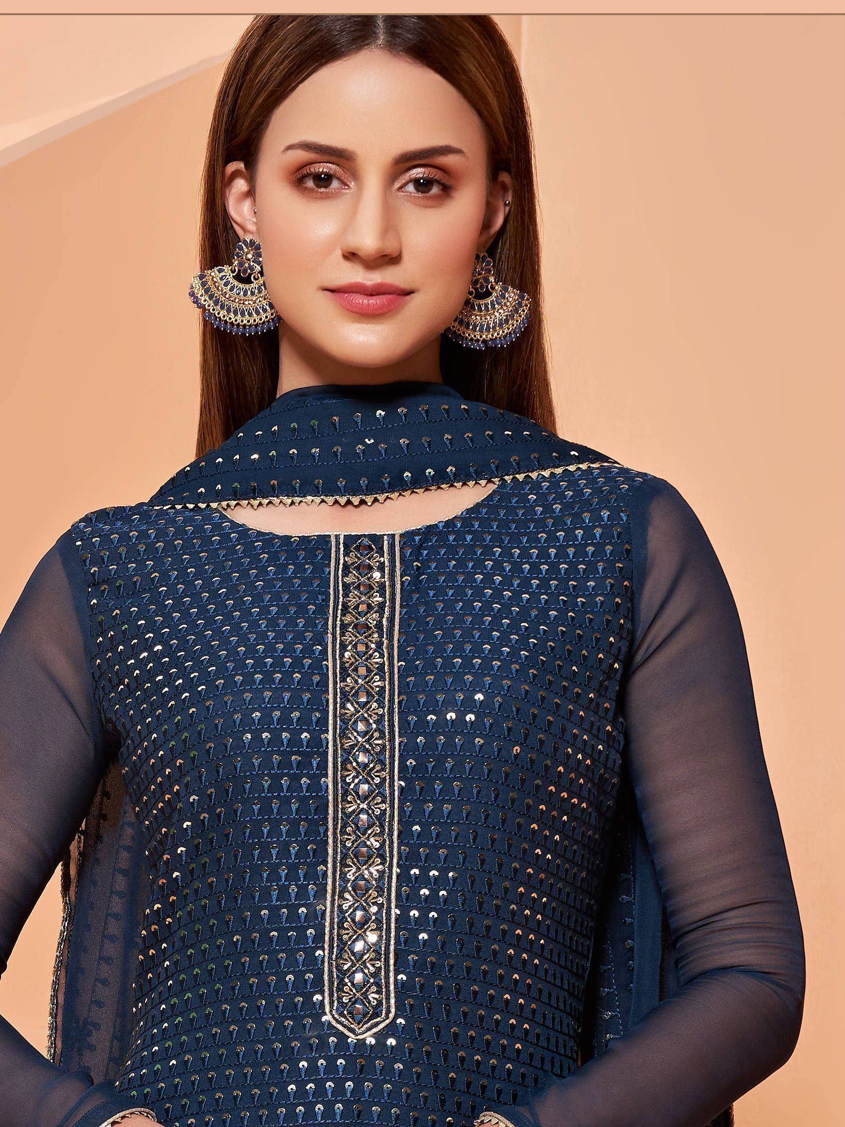 Navy blue embroidered ethnic kurti with sheer sleeves and gold detailing, paired with statement earrings.