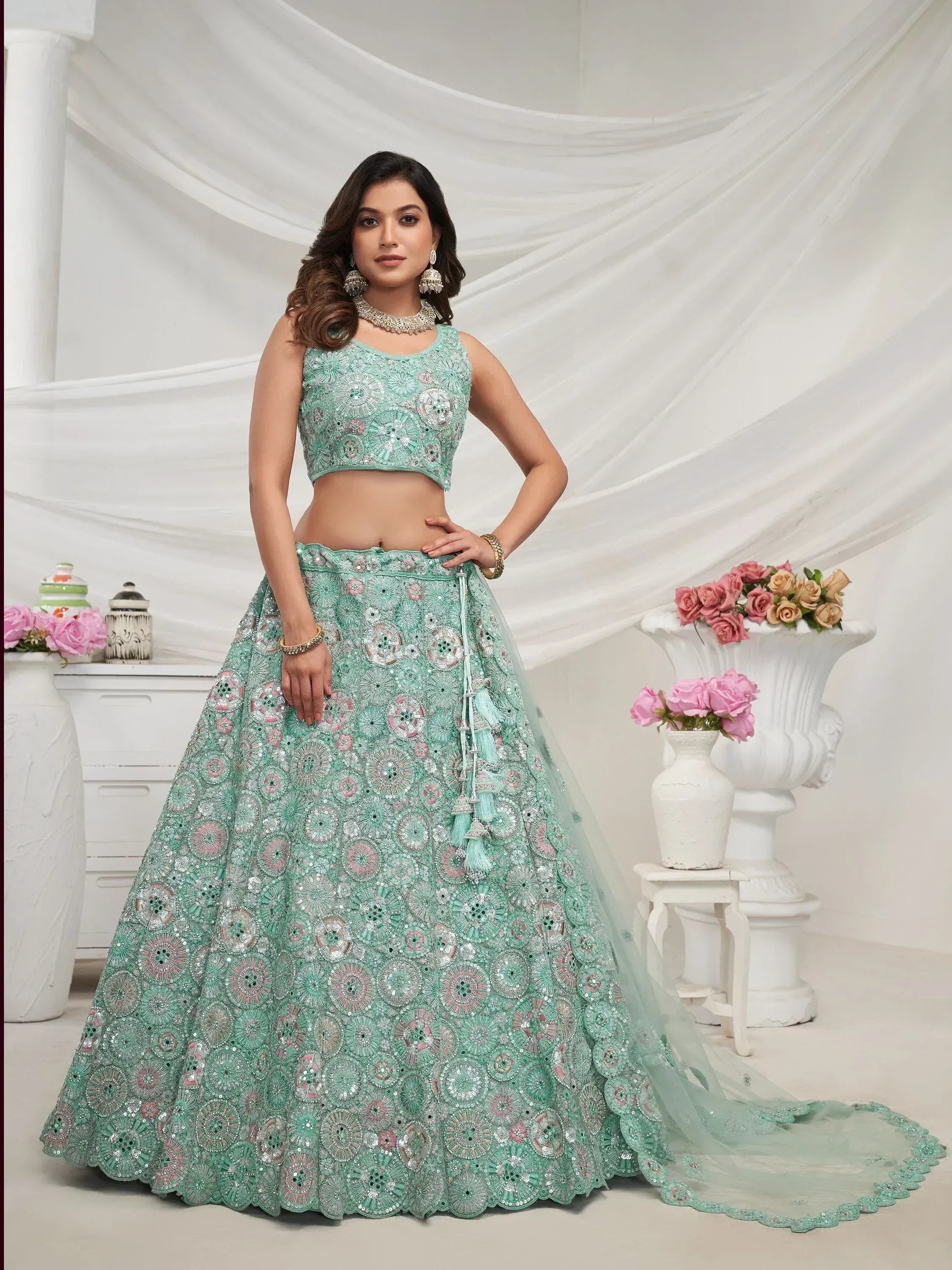Mint green designer lehenga choli with floral embroidery and tassels, perfect for Indian weddings and festive occasions.