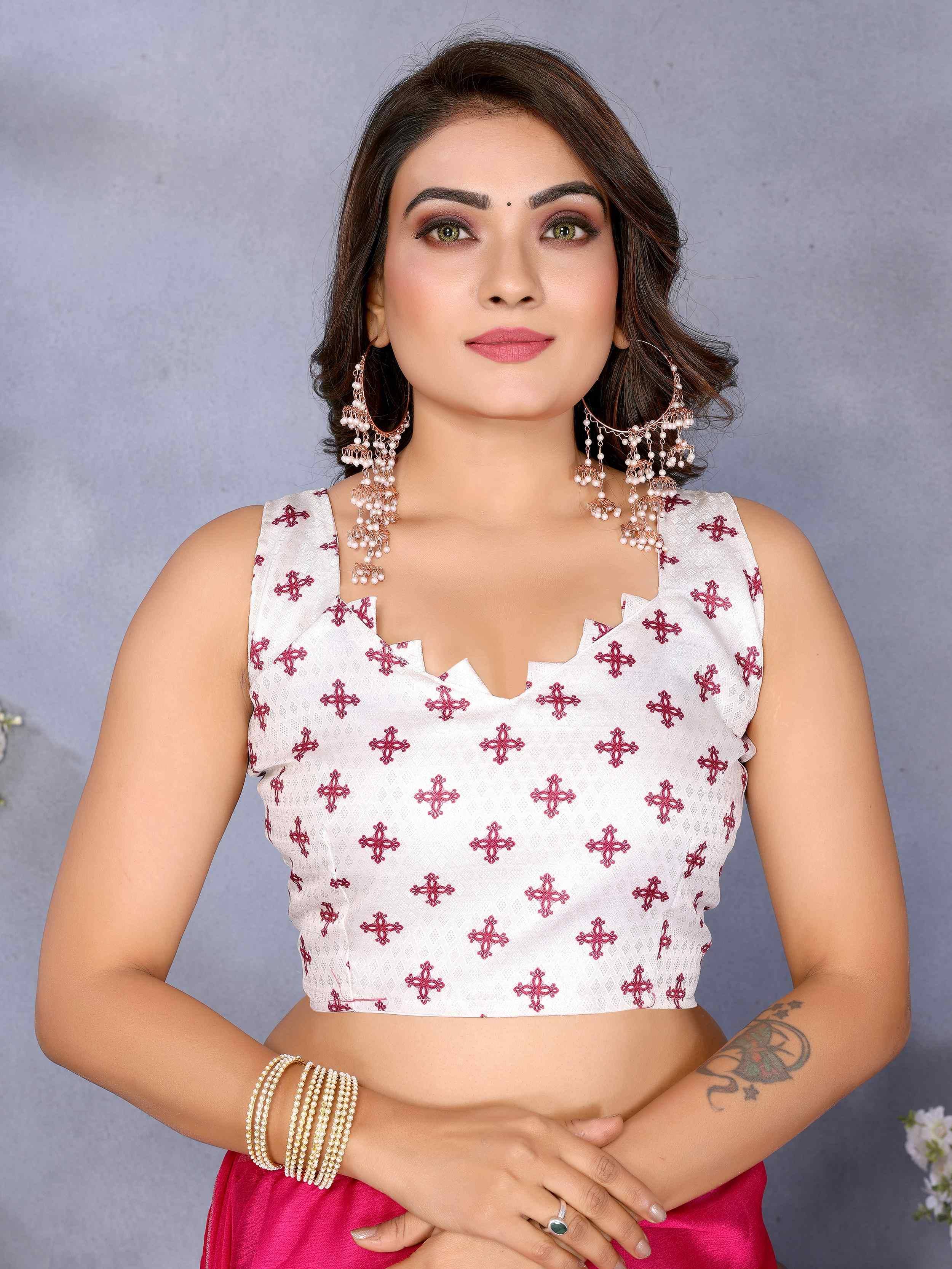 White embroidered crop top with red floral motifs, paired with pink skirt and pearl jewelry for ethnic wear