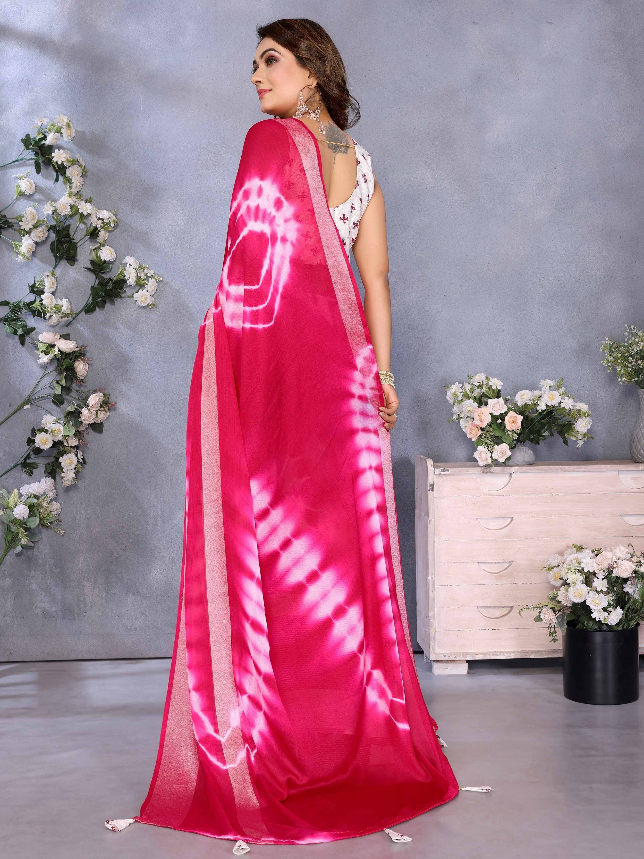 Woman in vibrant pink tie-dye saree with white blouse, floral backdrop, ethnic wear