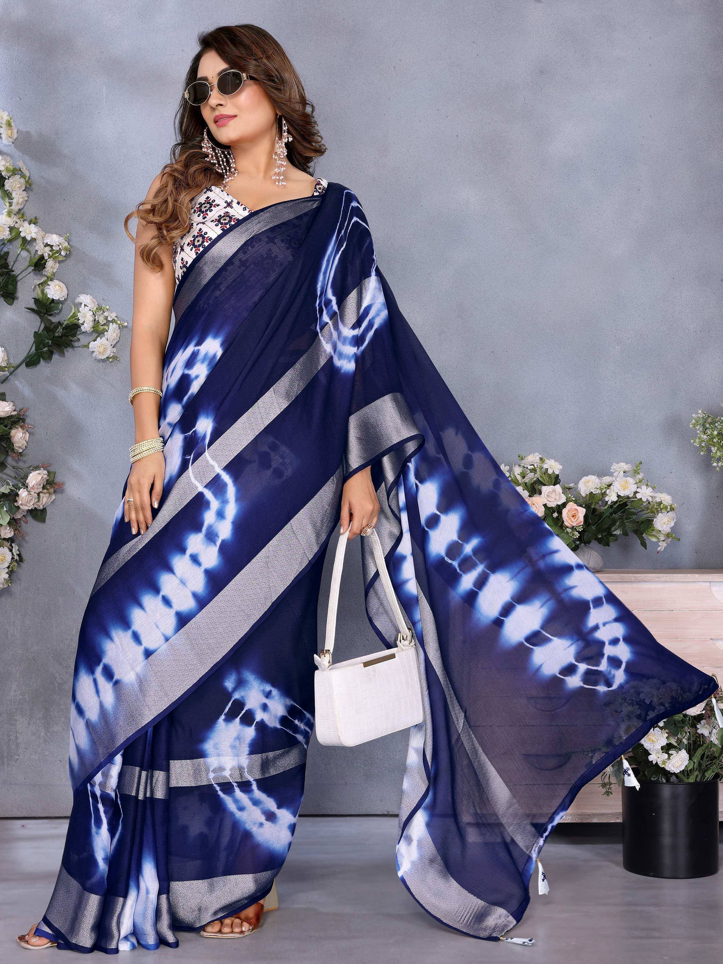Navy blue tie-dye saree with silver border, paired with floral blouse and white handbag, styled for ethnic wear.