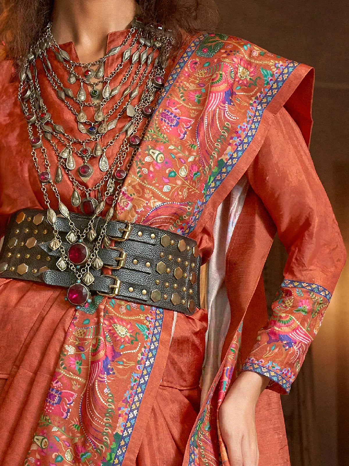 Orange embroidered ethnic gown with layered necklace and studded belt, perfect for Indian occasions