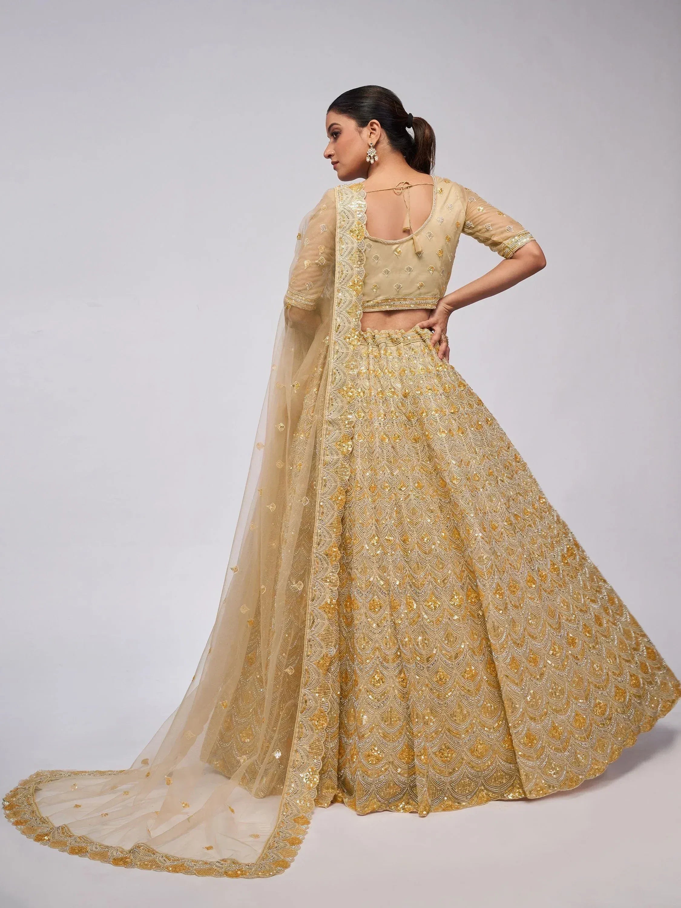 Elegant gold embroidered lehenga choli with sheer dupatta, perfect for Indian weddings and festive occasions.