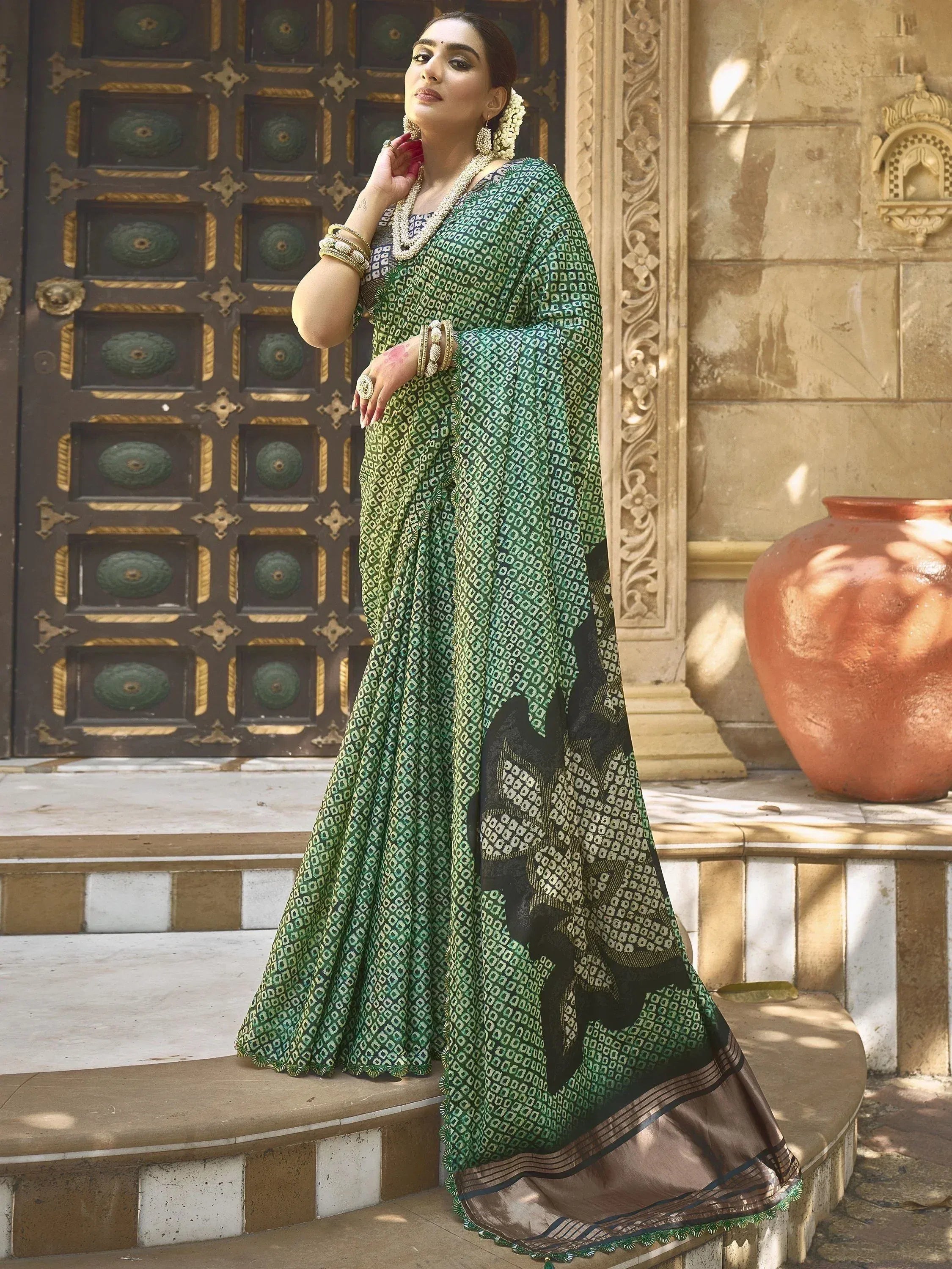 Woman in green printed saree with black border, traditional Indian ethnic wear, styled with gold jewelry