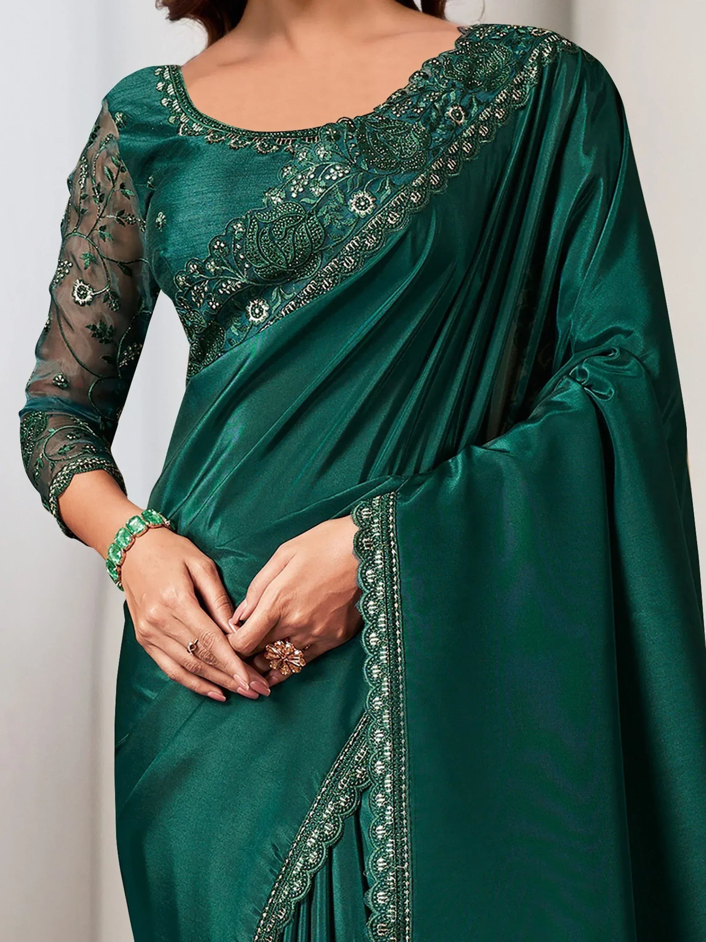 Emerald green satin saree with intricate floral embroidery and sheer sleeves, perfect for Indian ethnic wear.