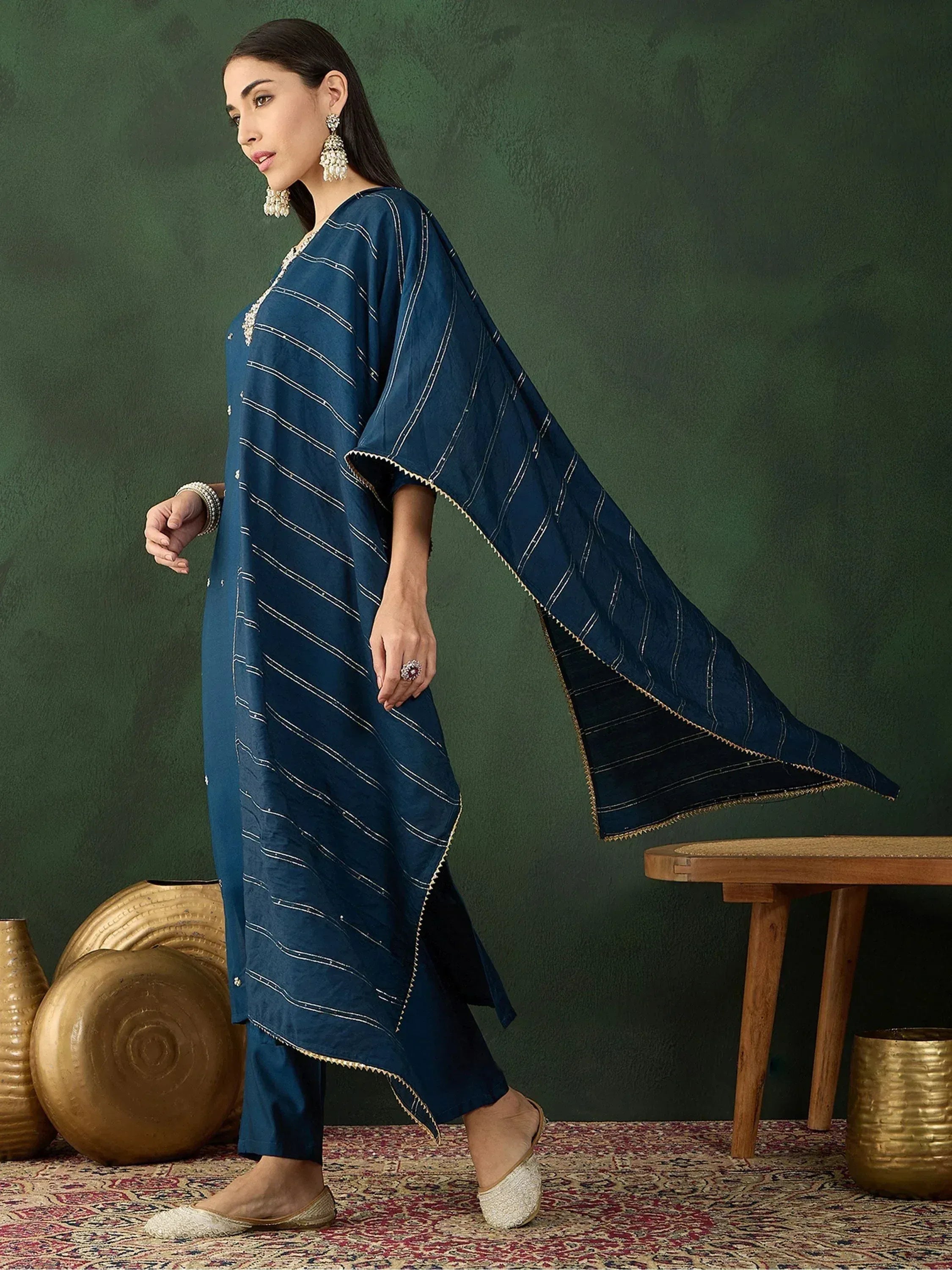 Navy blue ethnic kurta with gold stripes and cape sleeves, paired with matching pants and embellished flats