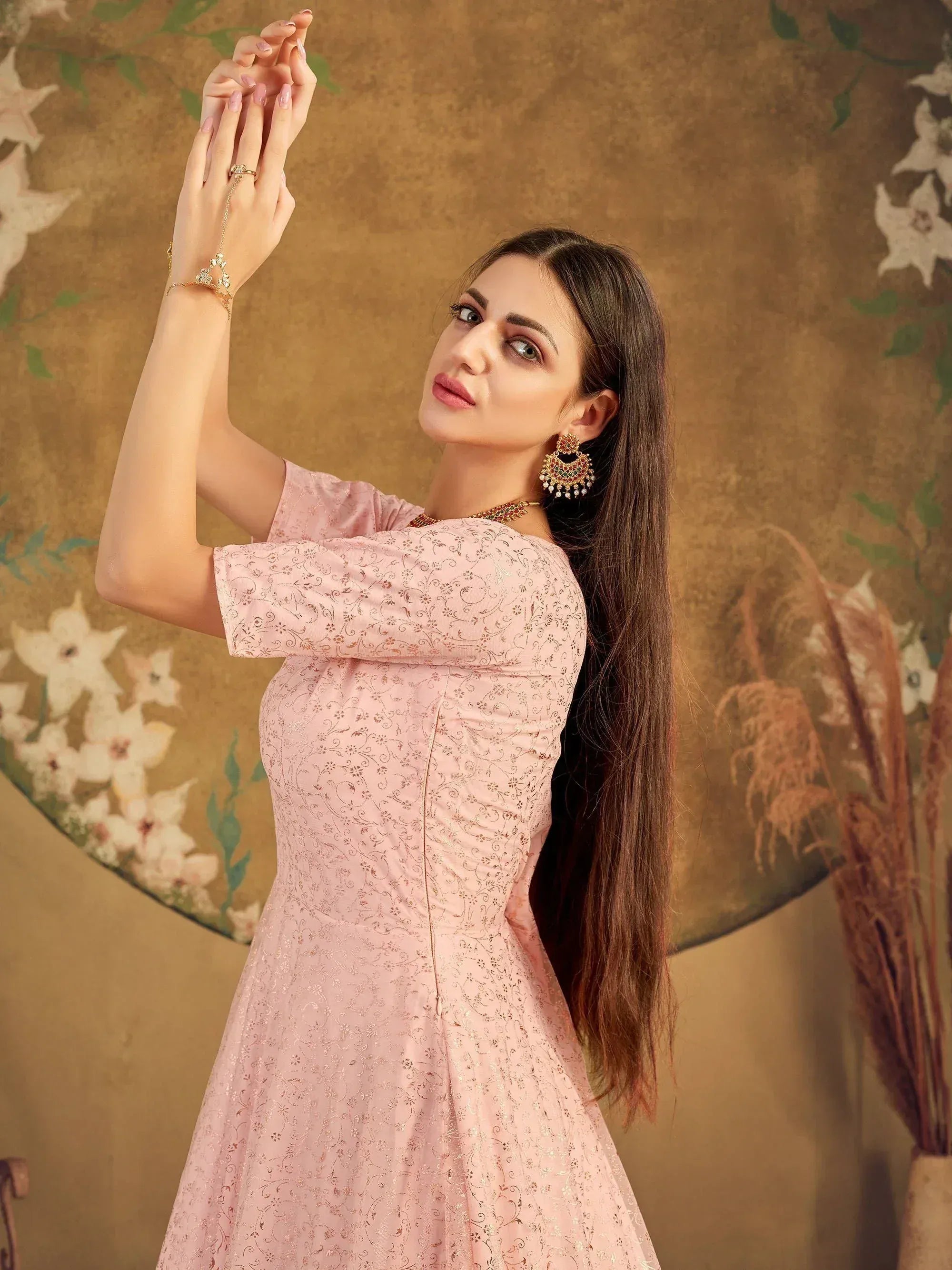 Pink embroidered ethnic gown with gold detailing, paired with traditional jewelry for festive occasions