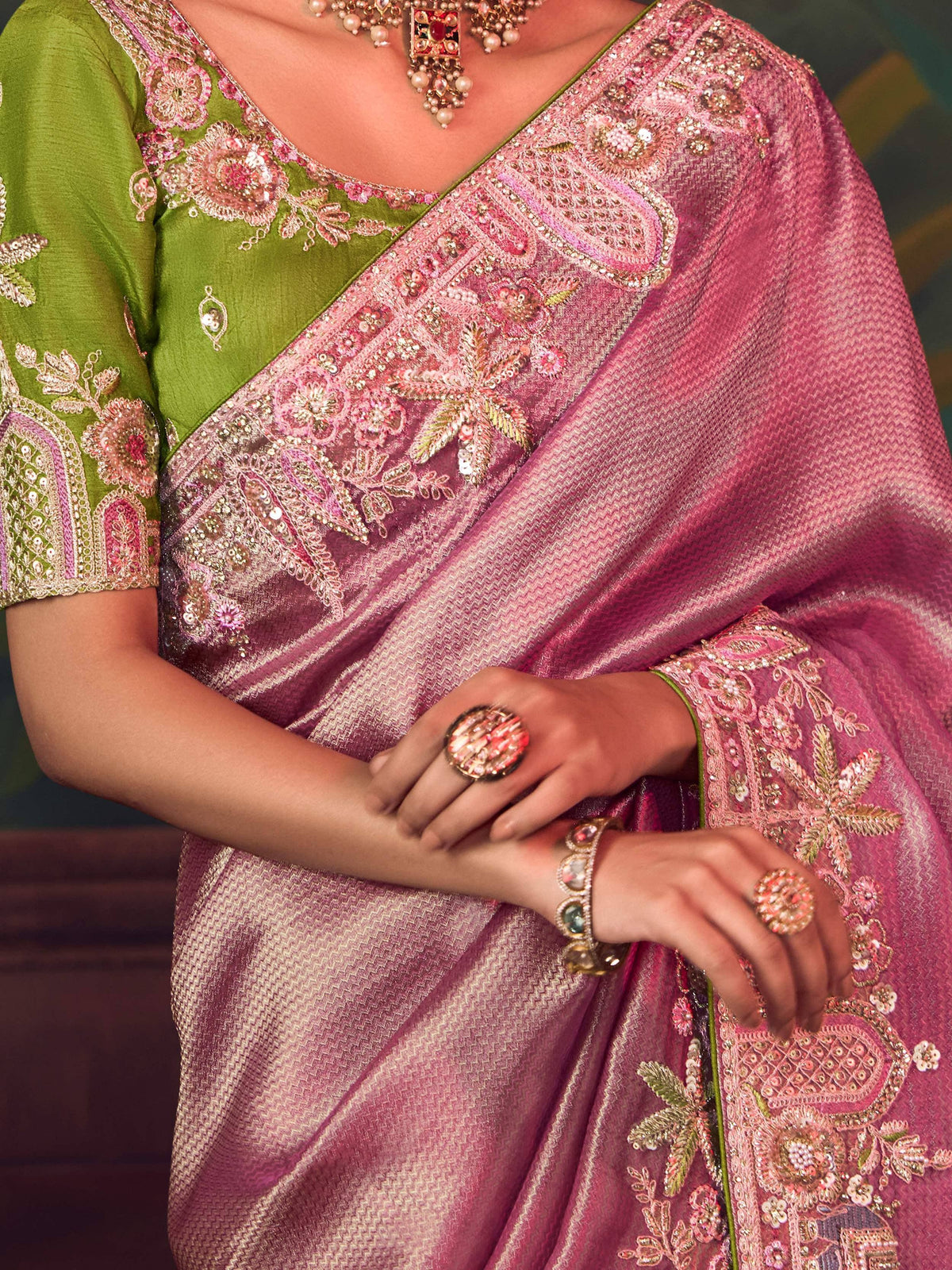 Elegant pink and green embroidered saree with intricate floral designs and traditional jewelry