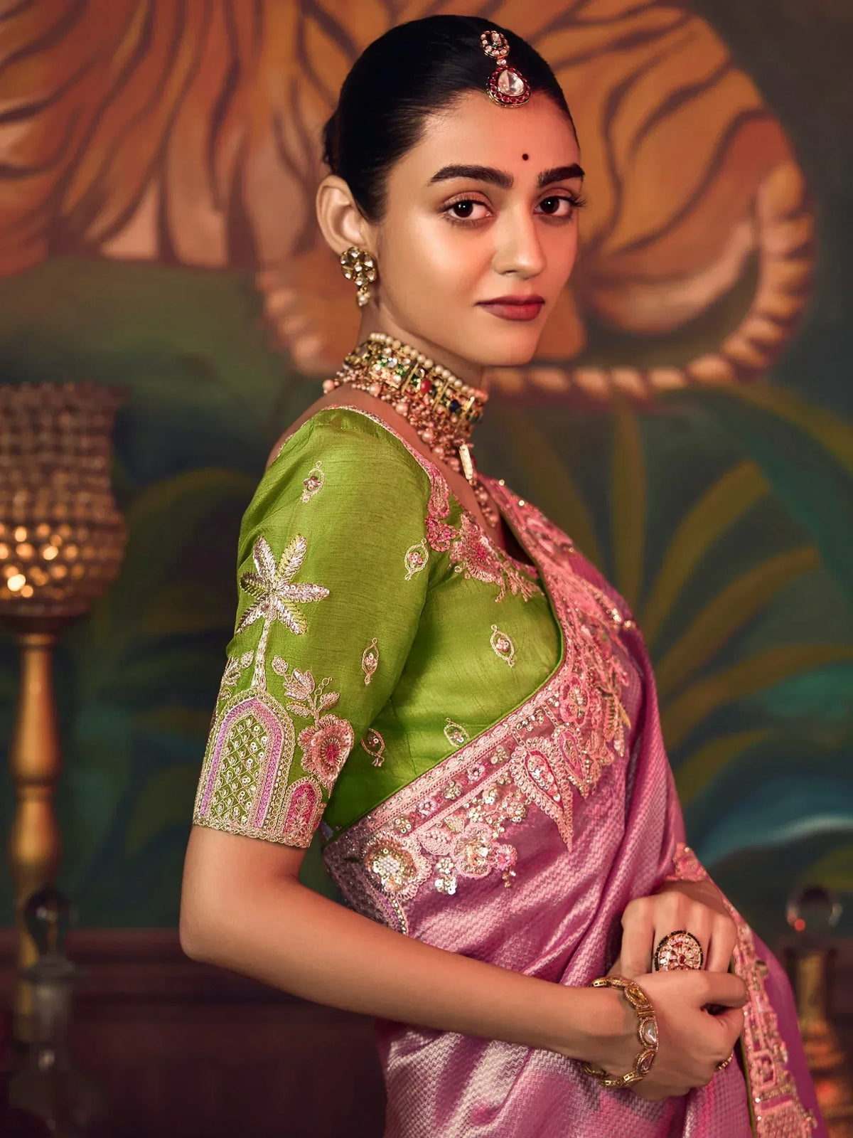 Elegant woman in green and pink embroidered saree with traditional jewelry