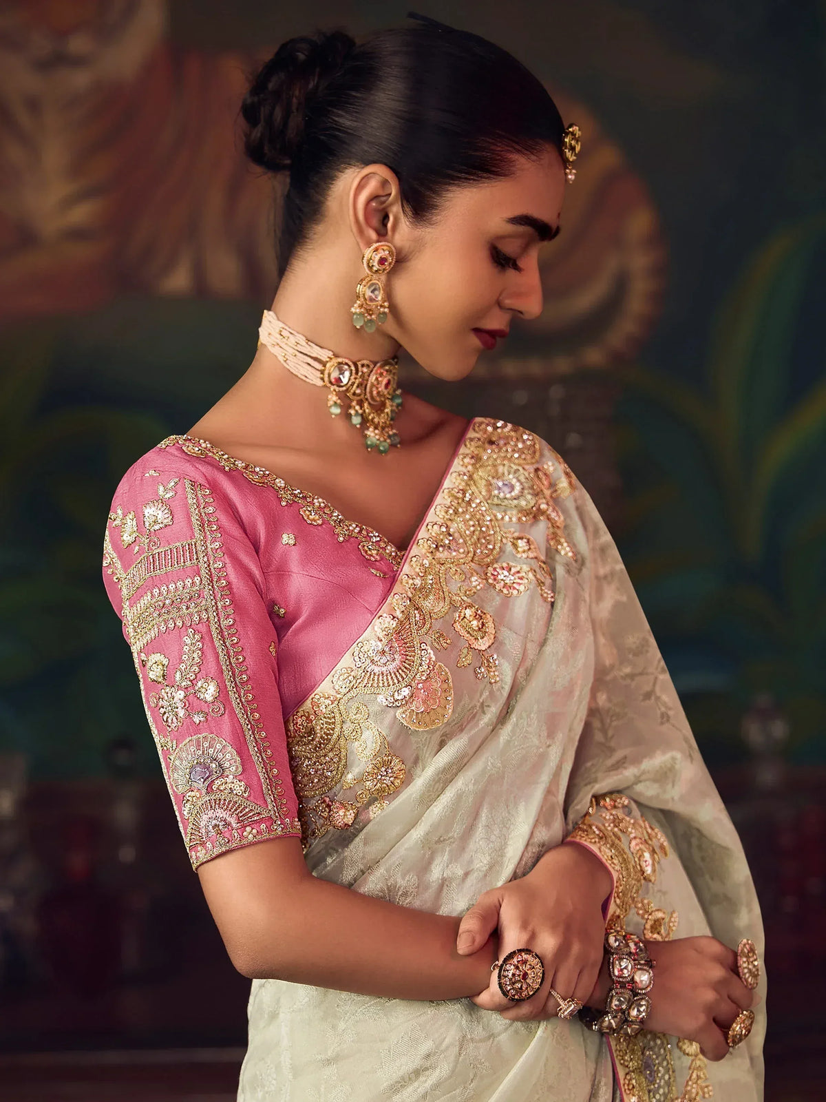 Elegant woman in embroidered saree with gold detailing and traditional jewelry